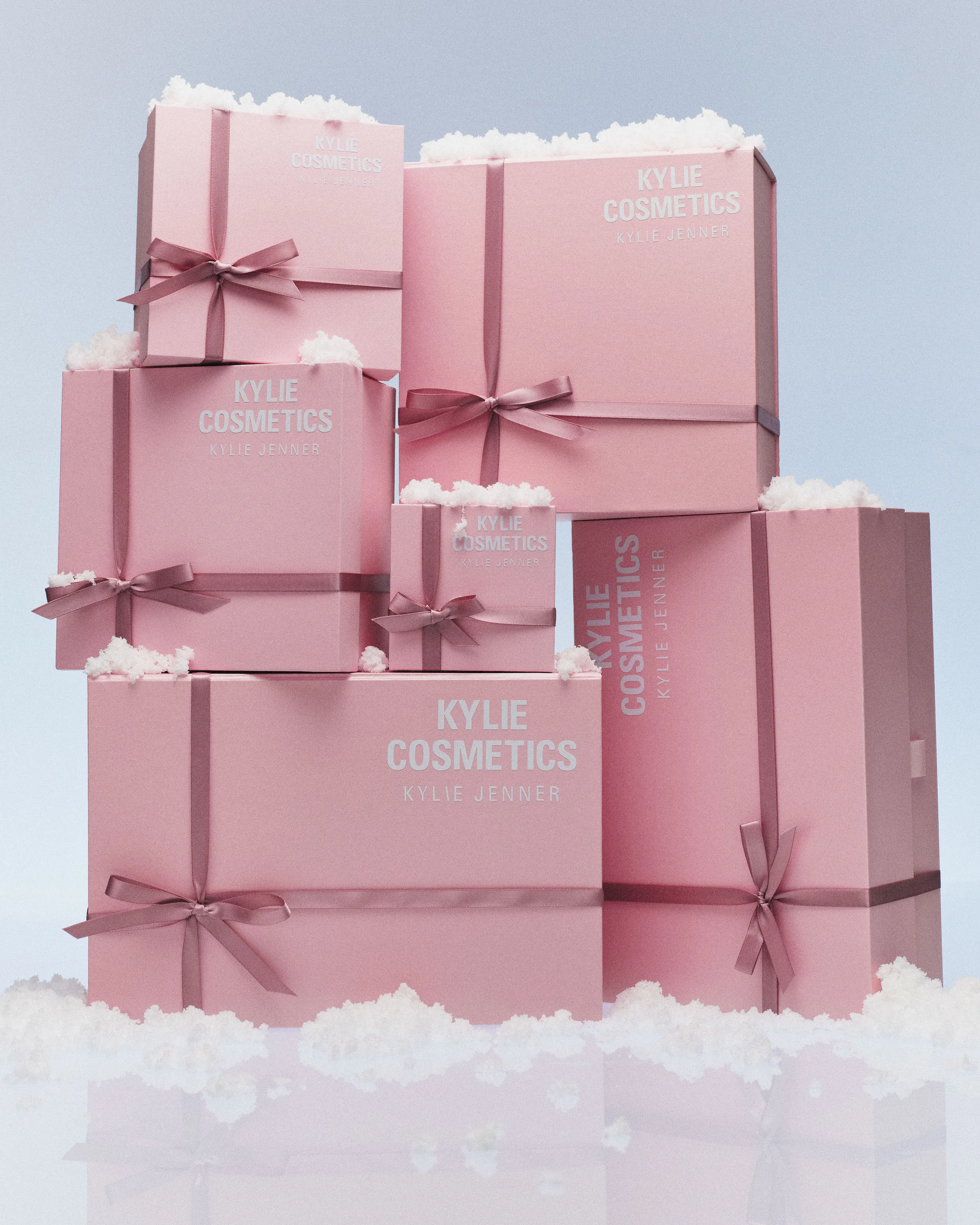 Stack of pink gift boxes tied with mauve satin bows, topped with fake snow on a pale blue backdrop, for Kylie Cosmetics.