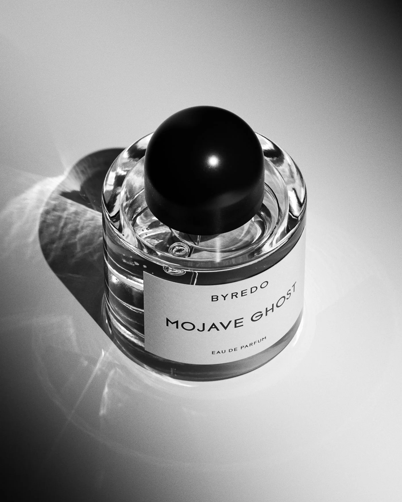 CGI render of a Mojave Ghost eau de parfum bottle with black cap casting sharp shadows in black and white, for Byredo.