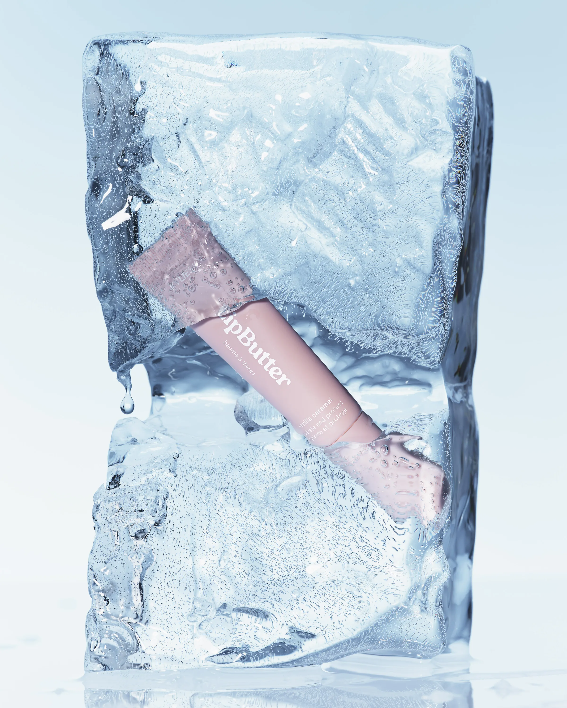 Pink Lip Butter tube frozen inside a dripping block of clear ice on a pale blue background, for Kylie Cosmetics.