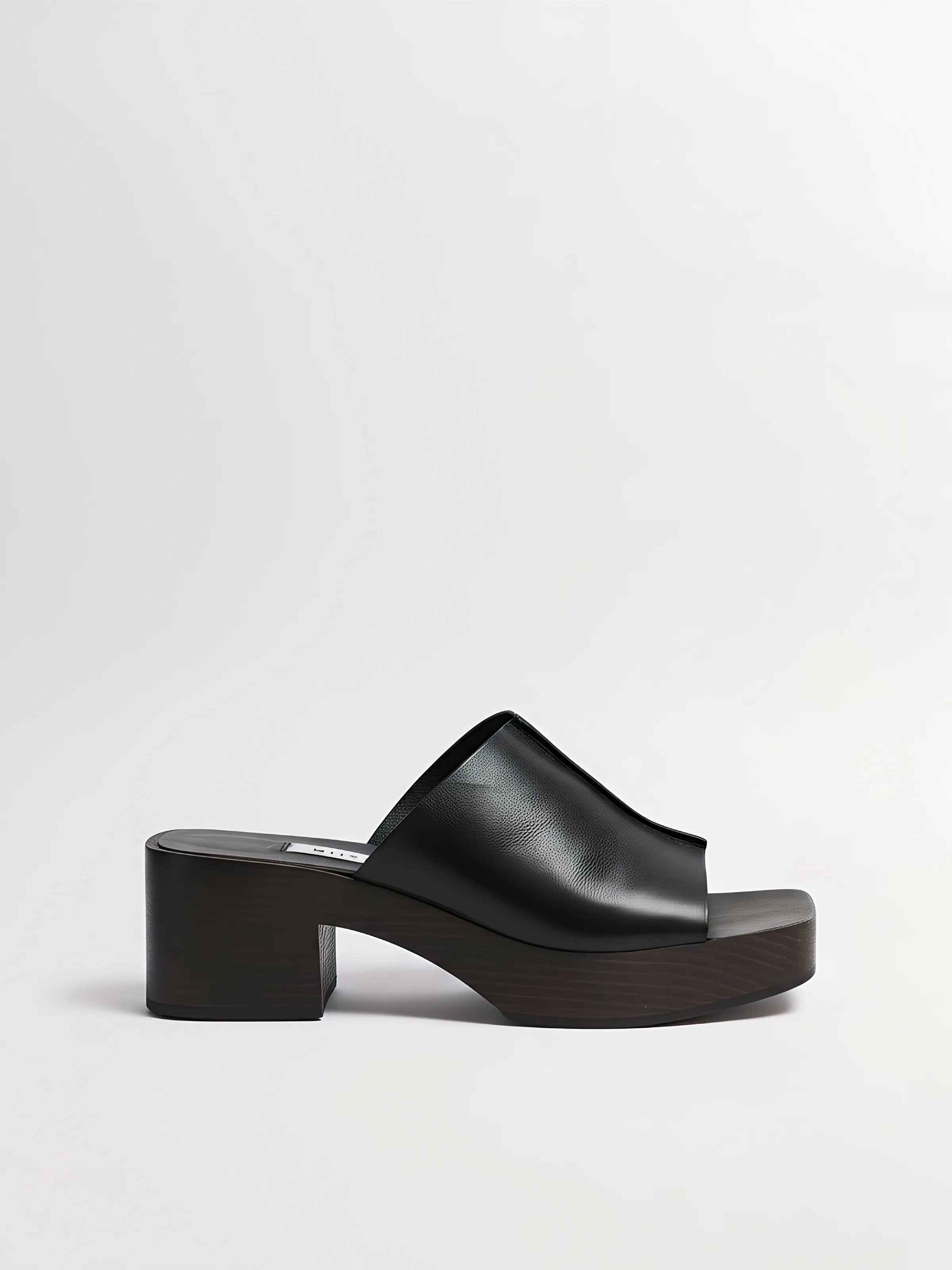 AI image of a black leather slide mule with a dark wooden block heel on a pale grey background. Miista AI Concept.