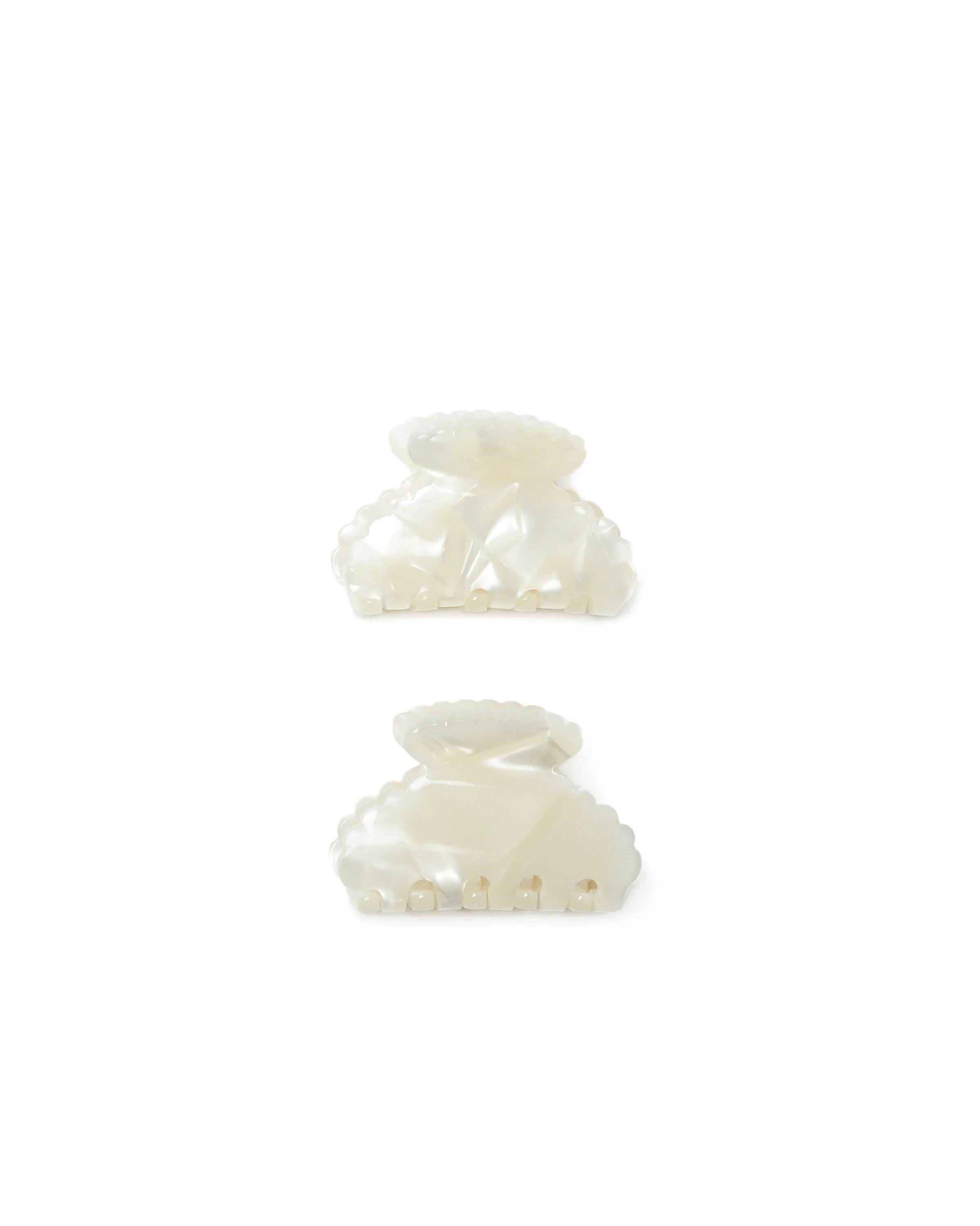 Pair of pearly cream scalloped claw hair clips on a white background, for Loeffler Randall.