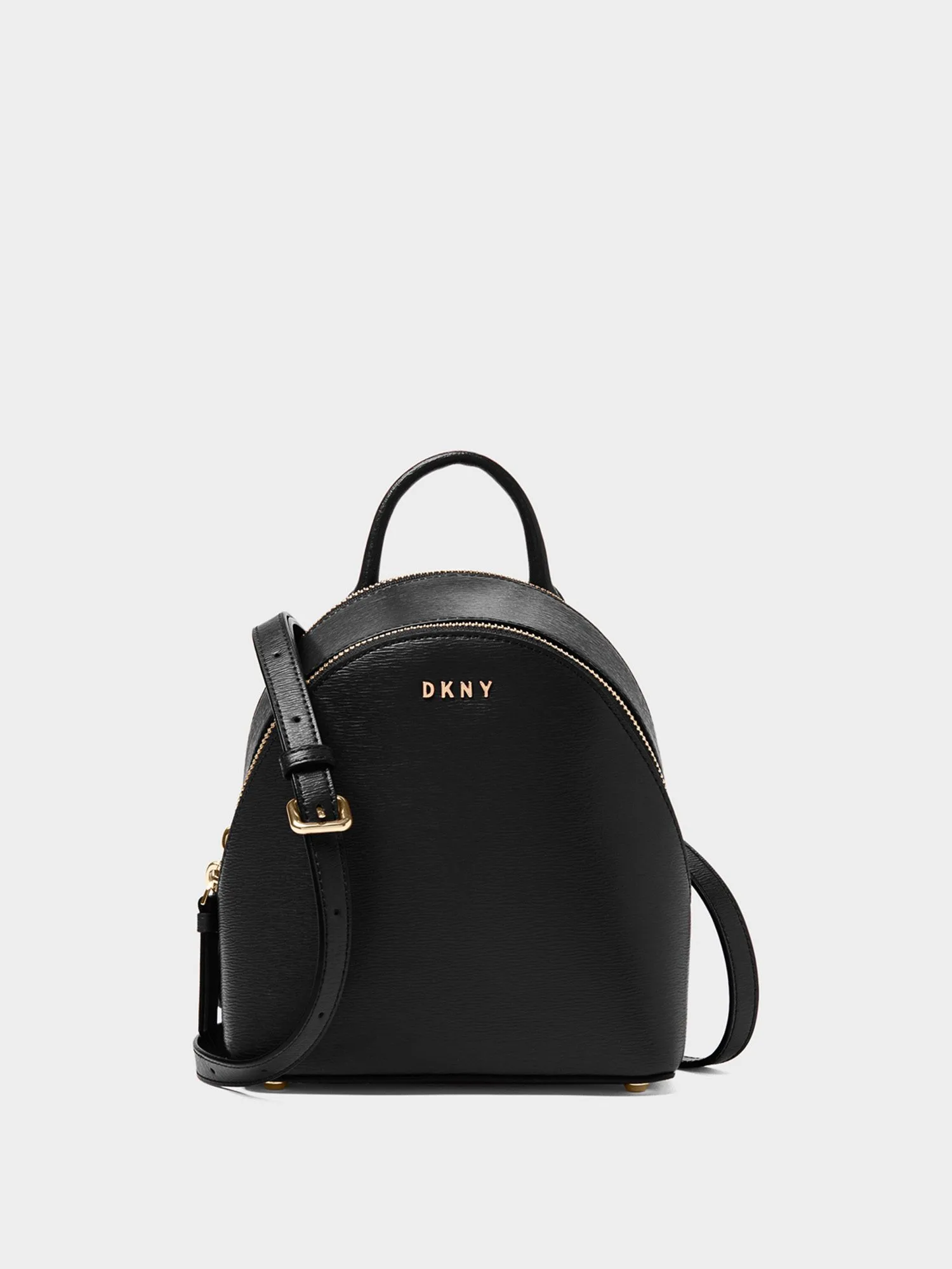 Black saffiano leather mini backpack with gold DKNY lettering, zip and crossbody strap on a white background, for DKNY.