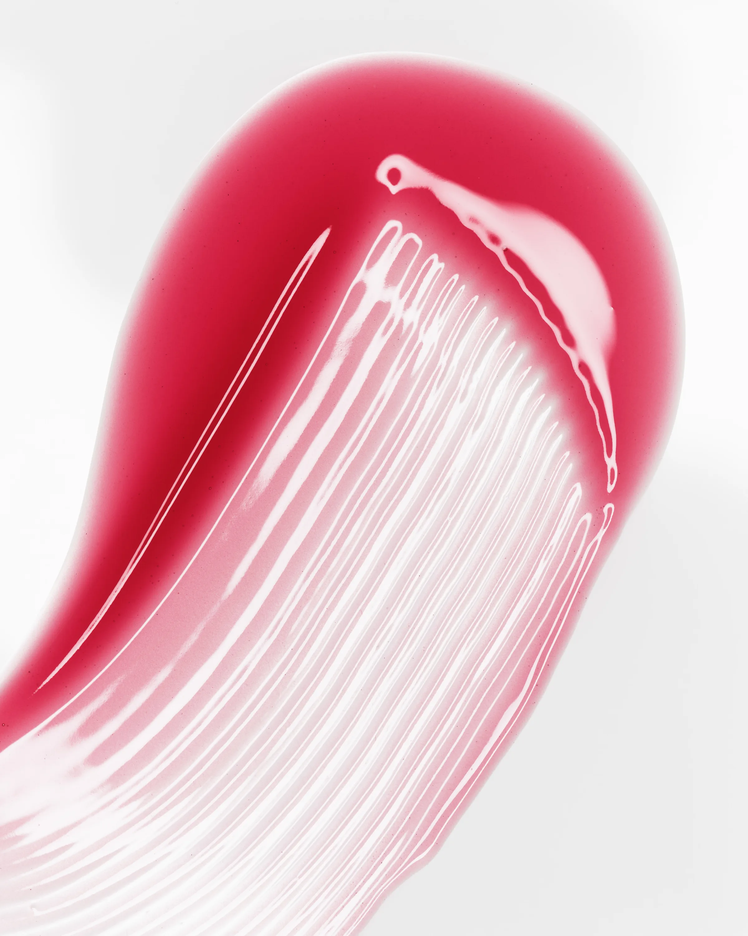 Glossy pink lip gloss swatch smeared across a white background with brush streaks, for Kylie Cosmetics.