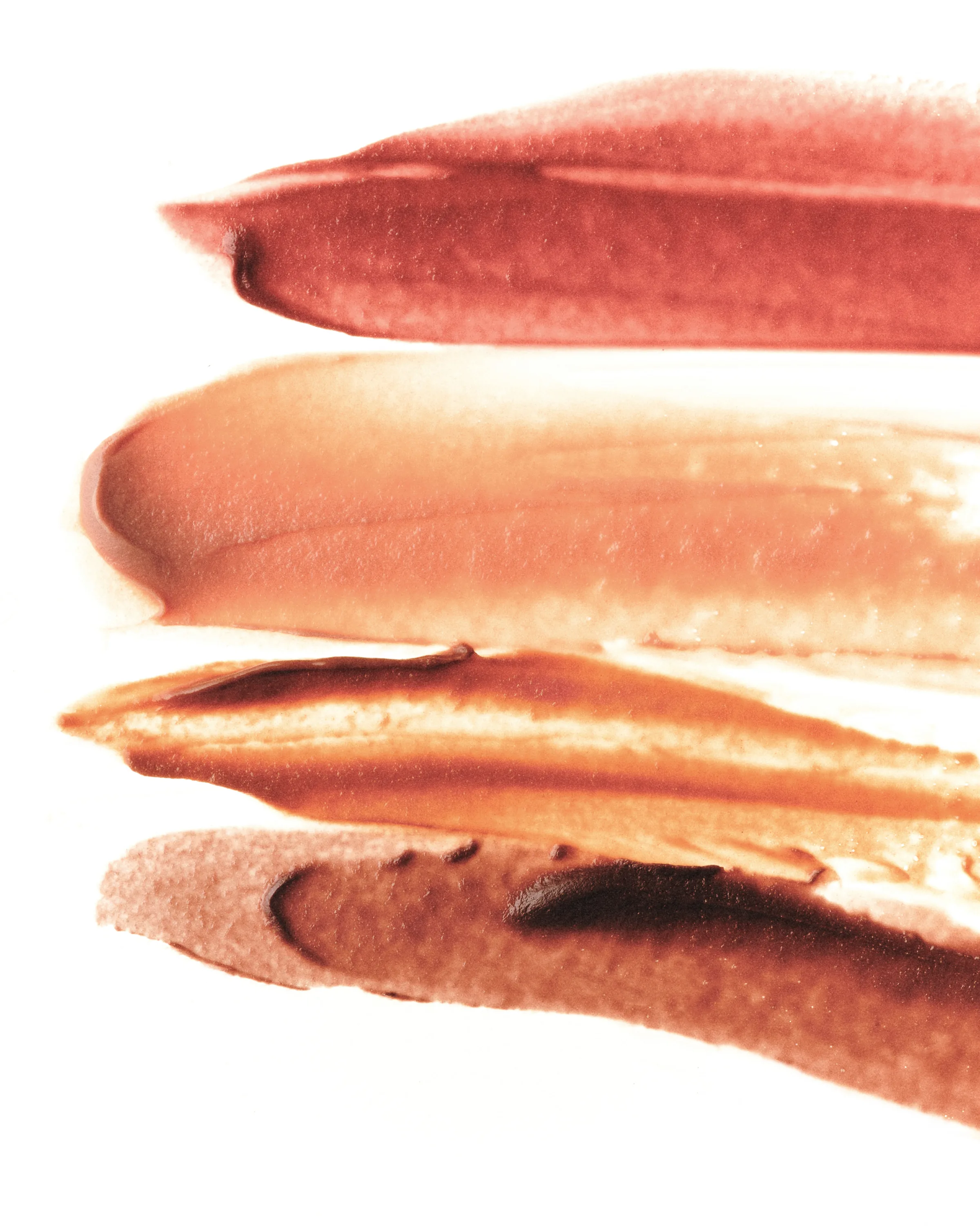 Four smeared cosmetic swatches in rose, peach, bronze and mauve on a white background, for Kylie Cosmetics.