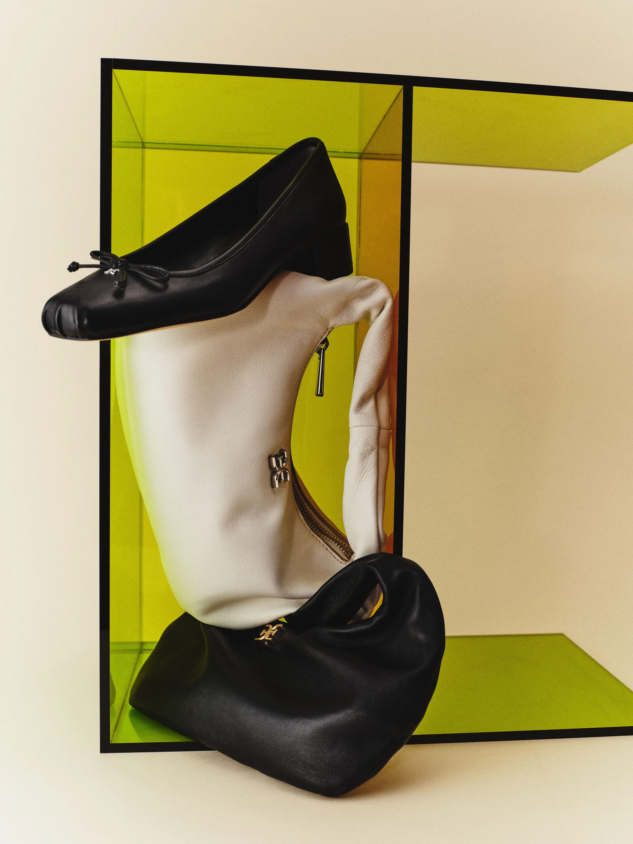 Black bow ballet heel balanced on white and black leather Michaela bags inside a lime acrylic box, for Sam Edelman.