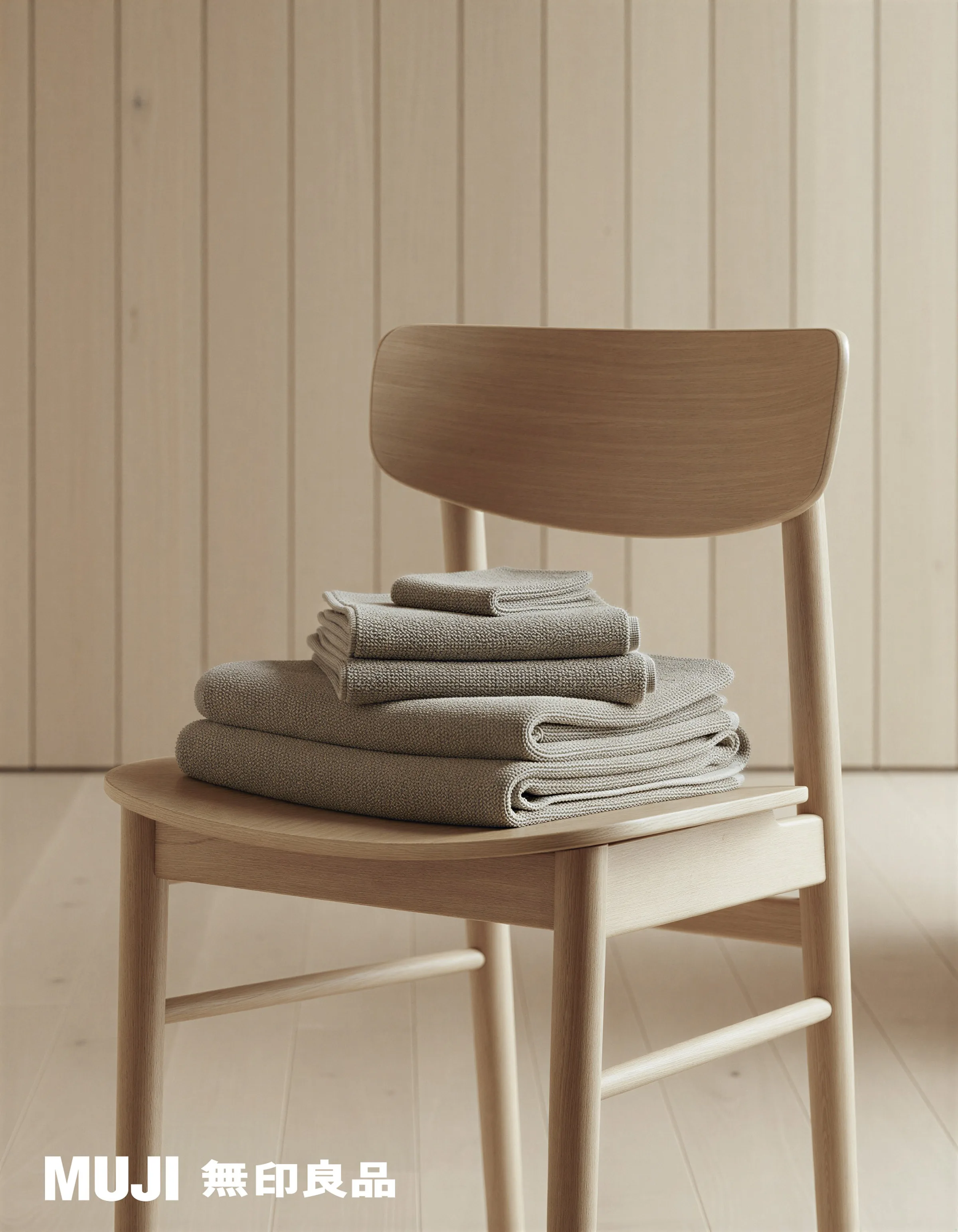 AI image of stacked taupe waffle towels on a pale wooden chair against a panelled wall. MUJI AI Concept.