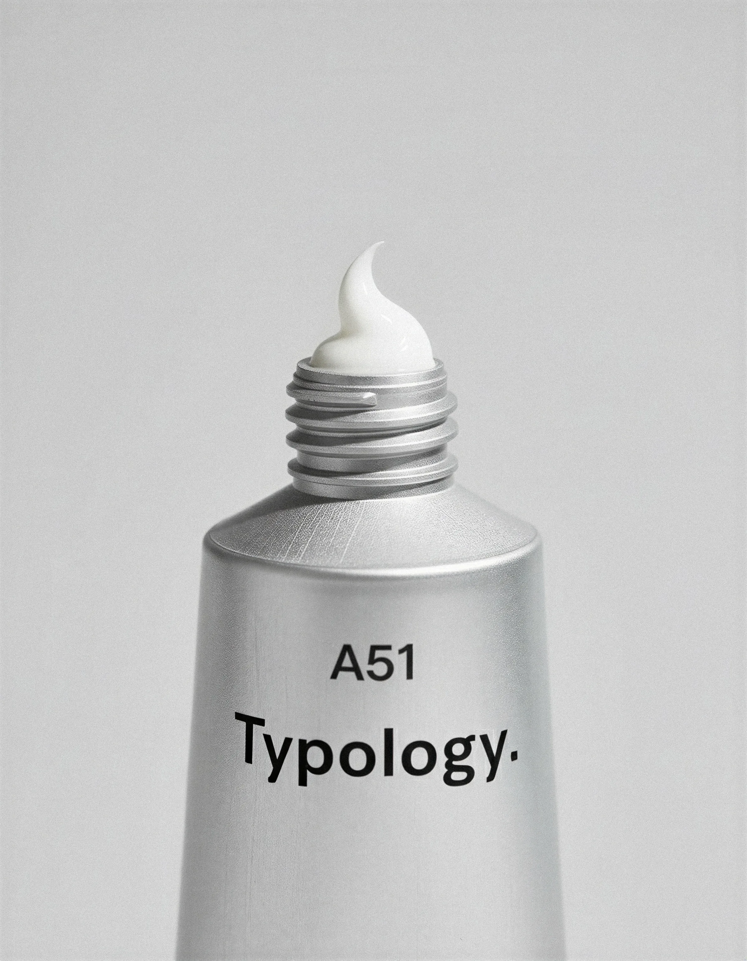 AI image of a brushed silver A51 tube with white cream curling from its open threaded neck on grey. Typology AI Concept.