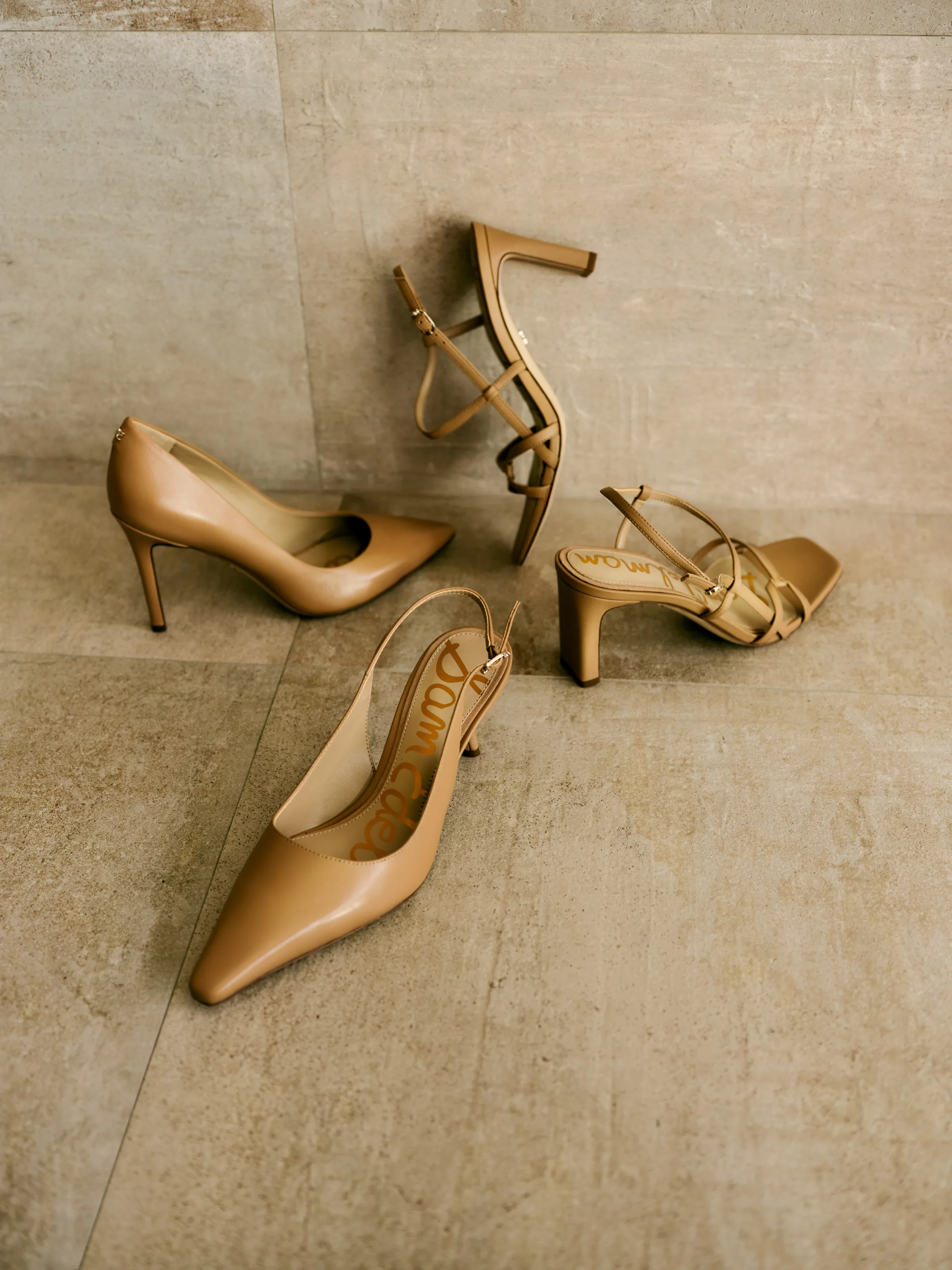 Tan leather pumps, slingback and strappy sandals scattered on a stone tile floor, for Sam Edelman.