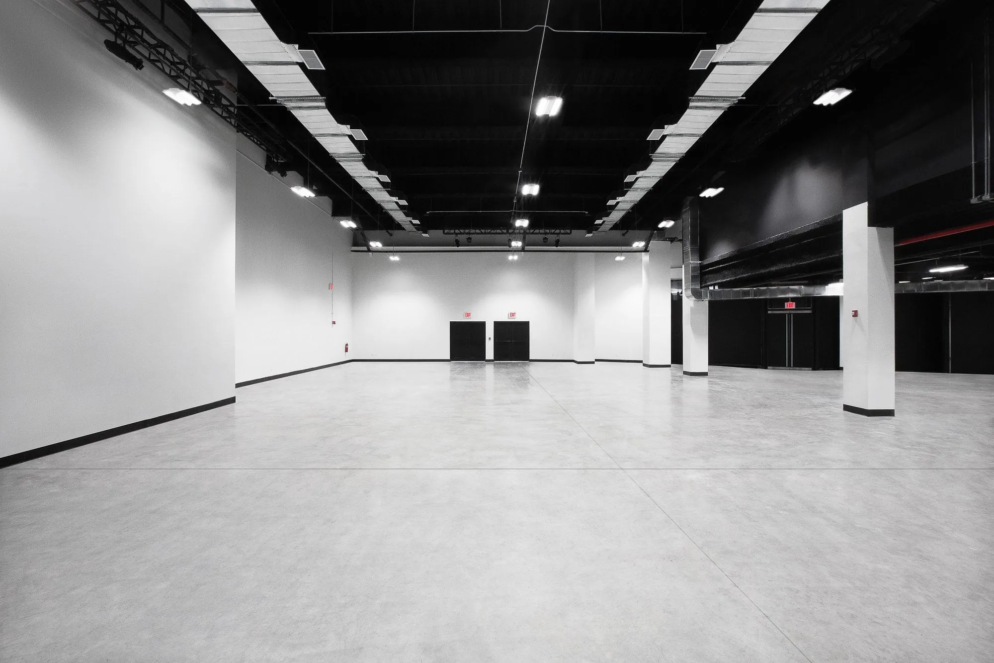 Empty Studio 2 stage at Slate Studios with white walls, black ceiling, grey concrete floor and support columns.