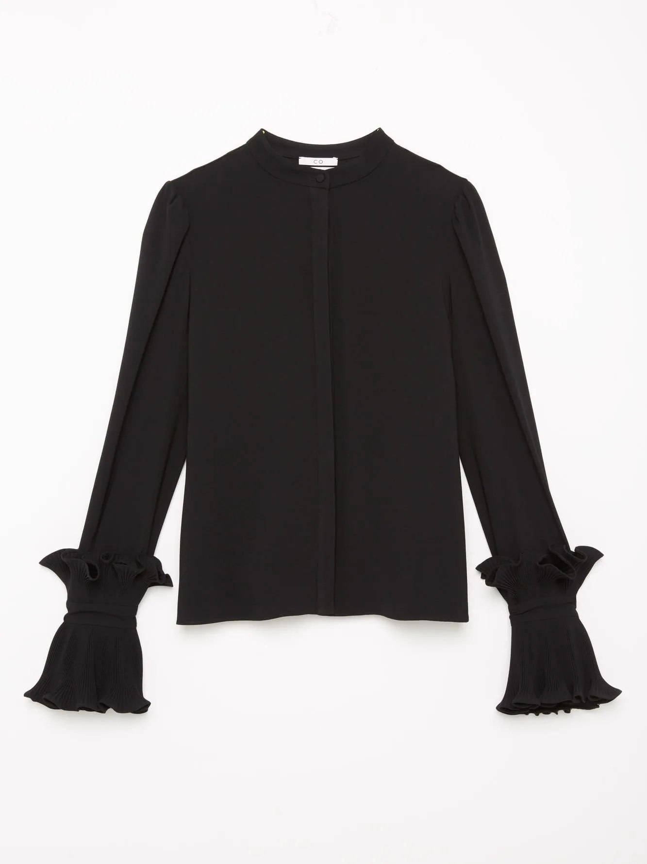 Black band-collar blouse with ruffled pleated cuffs laid flat on a white background, for Co Collections.