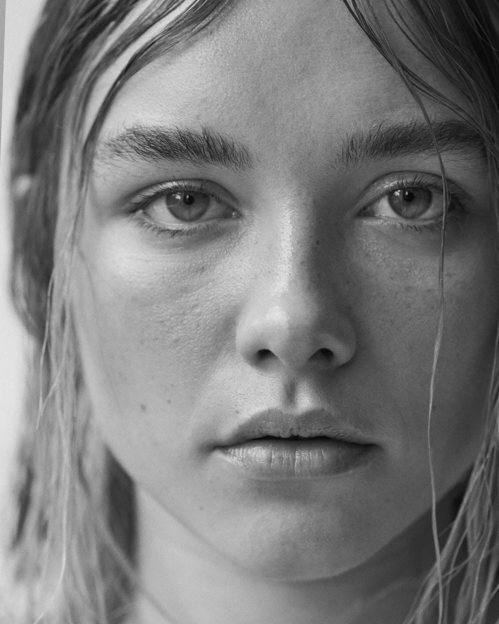Black and white close-up portrait of a woman with wet hair and freckled skin, for The Last Magazine.