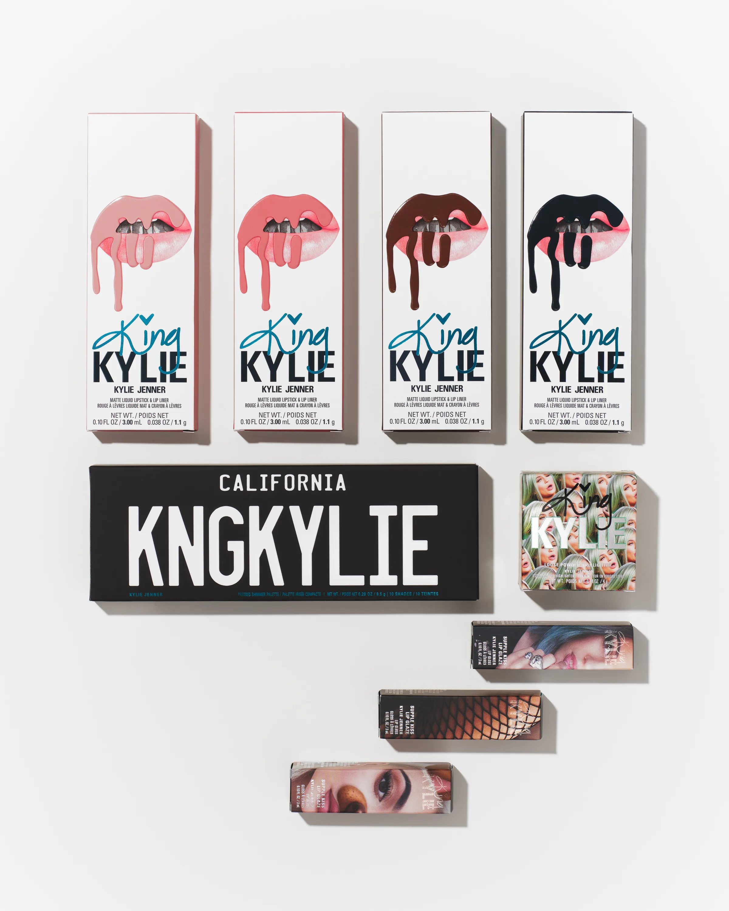 Flat lay of King Kylie lip kit boxes, KNGKYLIE palette and lipstick cartons on white, for Kylie Cosmetics.