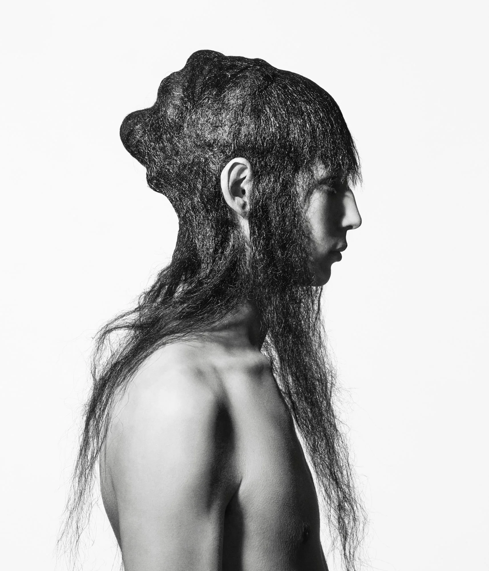 Black-and-white profile of a shirtless model with long, sculpted dark hair covering the head and face, for The Last Magazine.