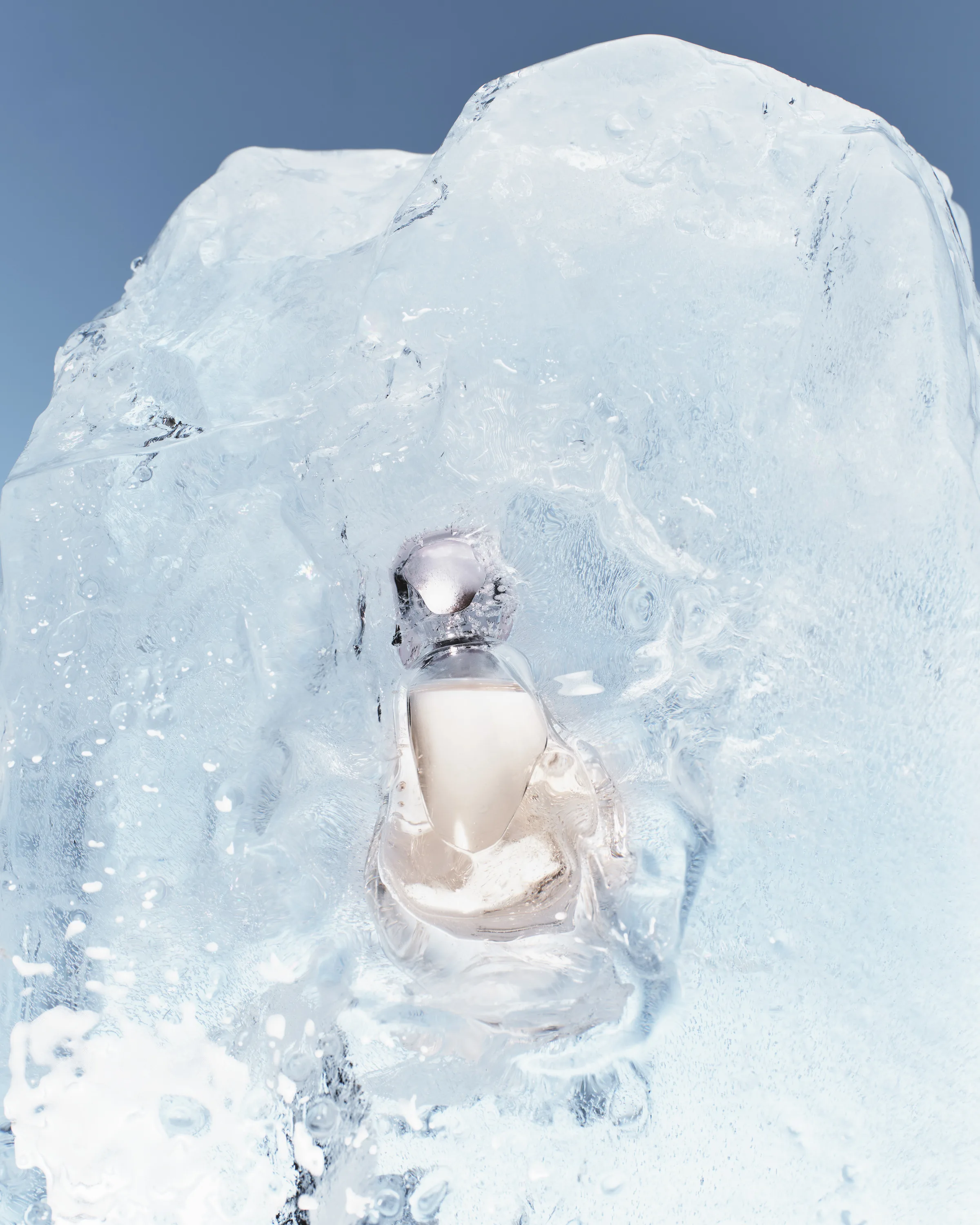 Pale pink perfume bottle encased in a block of clear ice against a blue sky backdrop, for Kylie Cosmetics.
