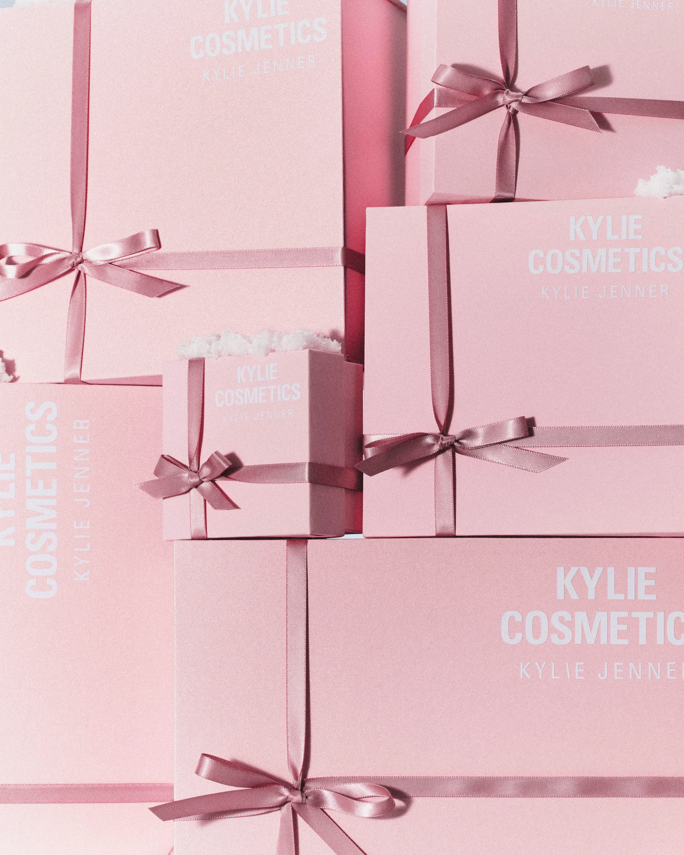 Stacked pink gift boxes tied with satin ribbon bows and dusted with white frost, for Kylie Cosmetics.
