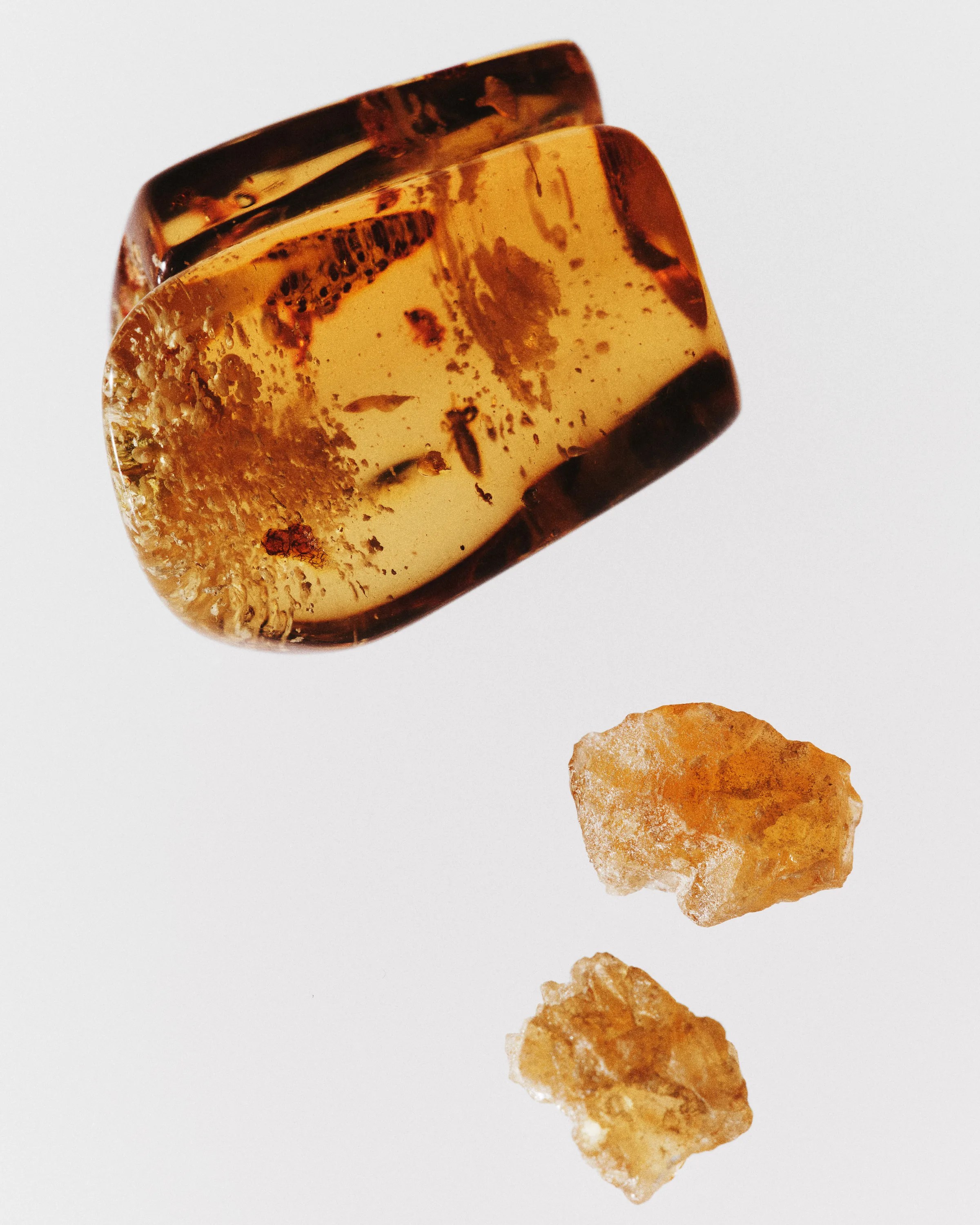 Still life of a polished amber stone and two rough benzoin resin pieces on a white background, for Kylie Cosmetics.
