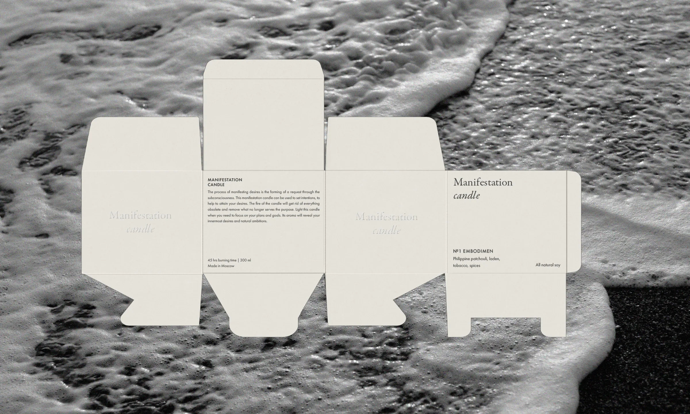 Unfolded cream candle box dieline with serif type and product text, laid over a black-and-white sea foam photo, for Manifestation.