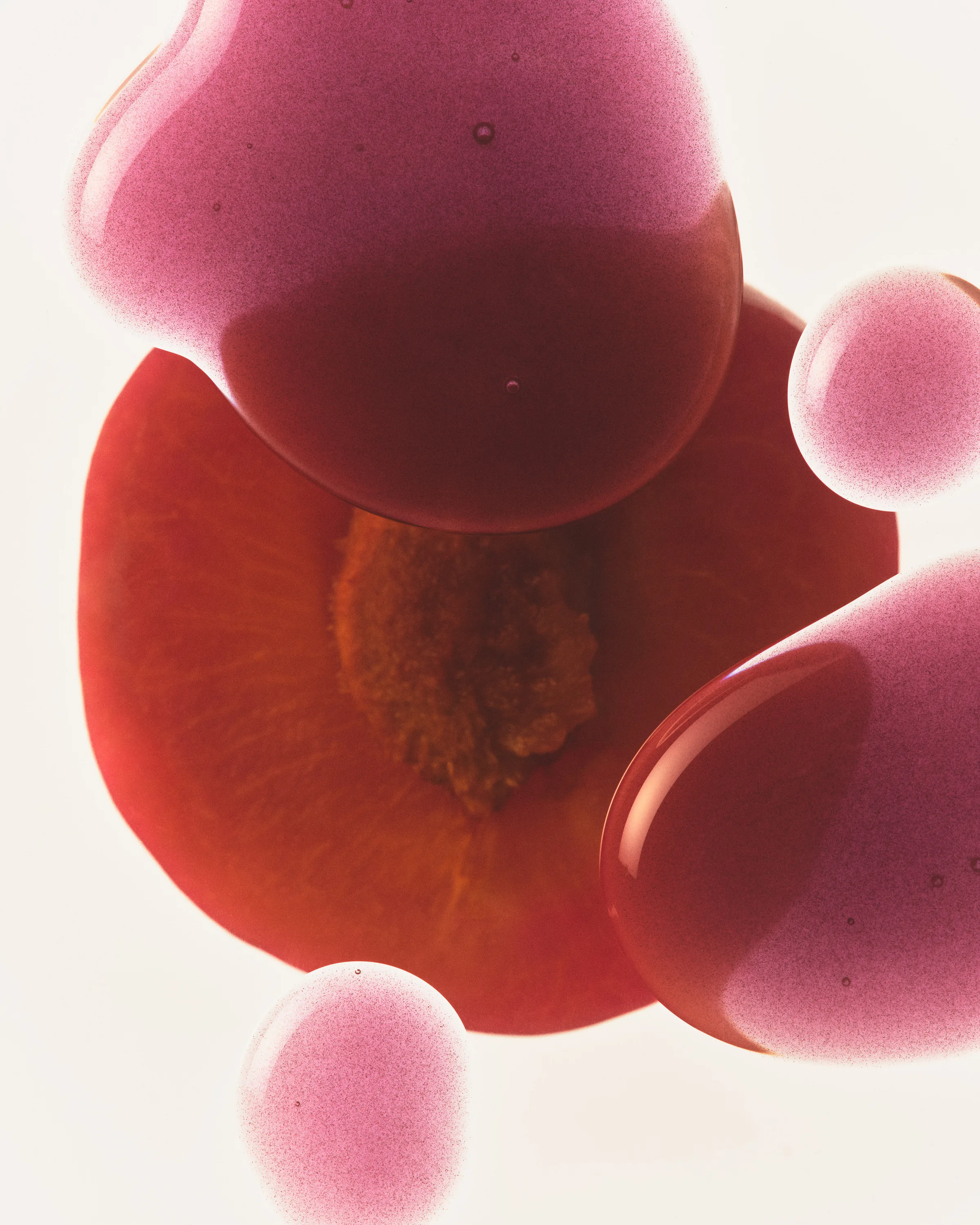 Pink-plum lip gloss droplets floating over a sliced plum on a white background, for Kylie Cosmetics.