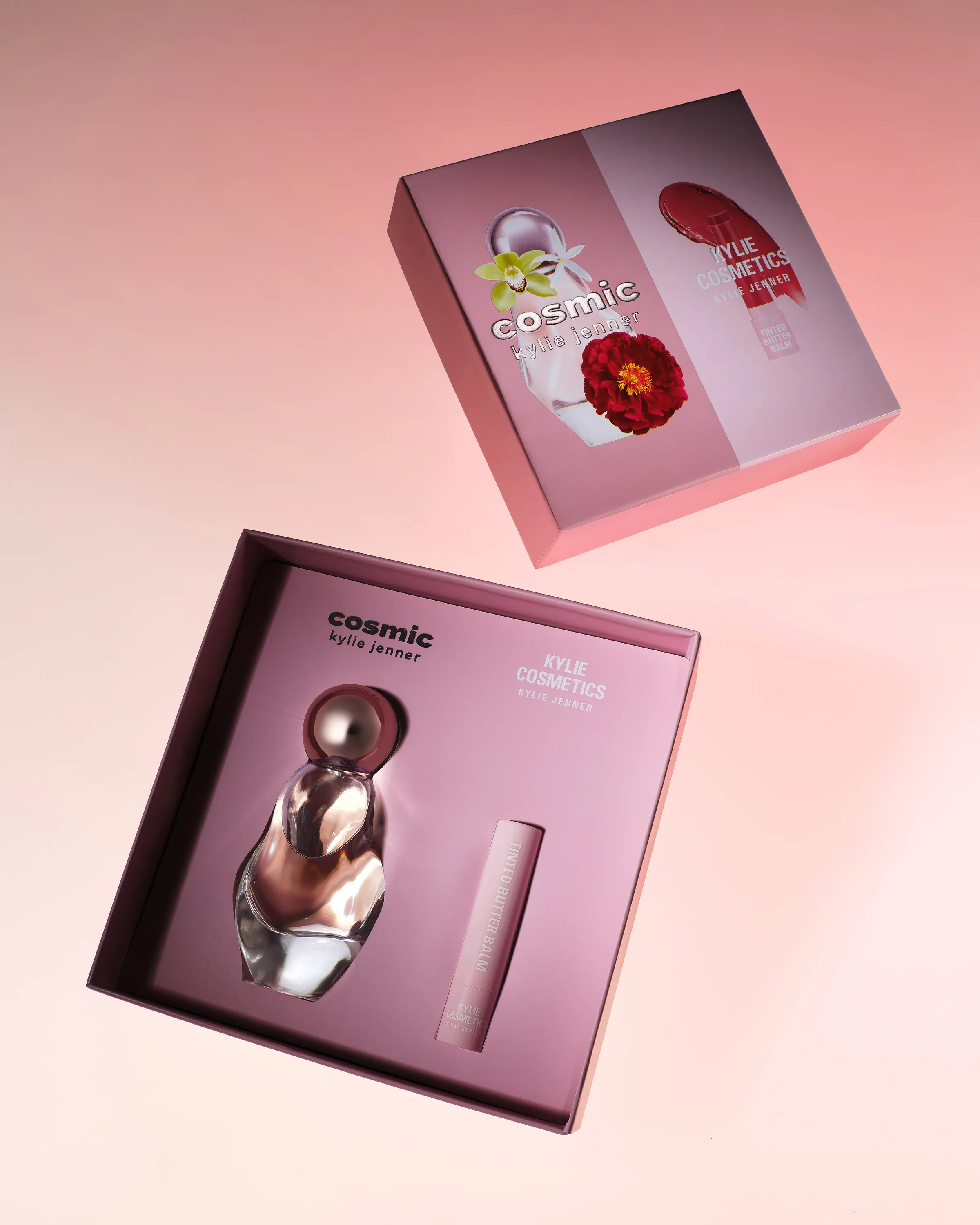 Open pink gift box with Cosmic perfume bottle and tinted butter balm, lid floating above on a pink gradient, for Kylie Cosmetics.