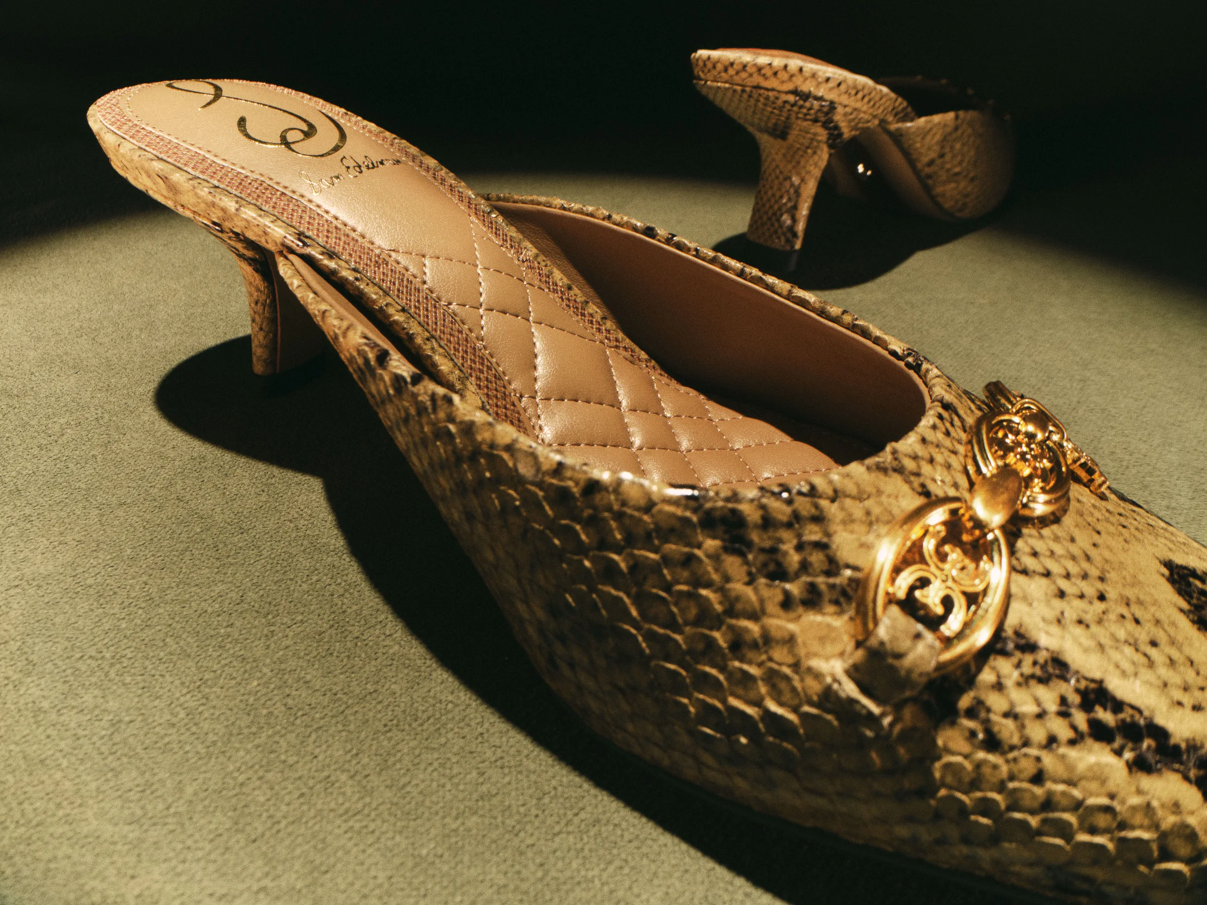 Golden tan snake-embossed kitten heel mules with quilted insole and gold logo hardware on green felt, for Sam Edelman.