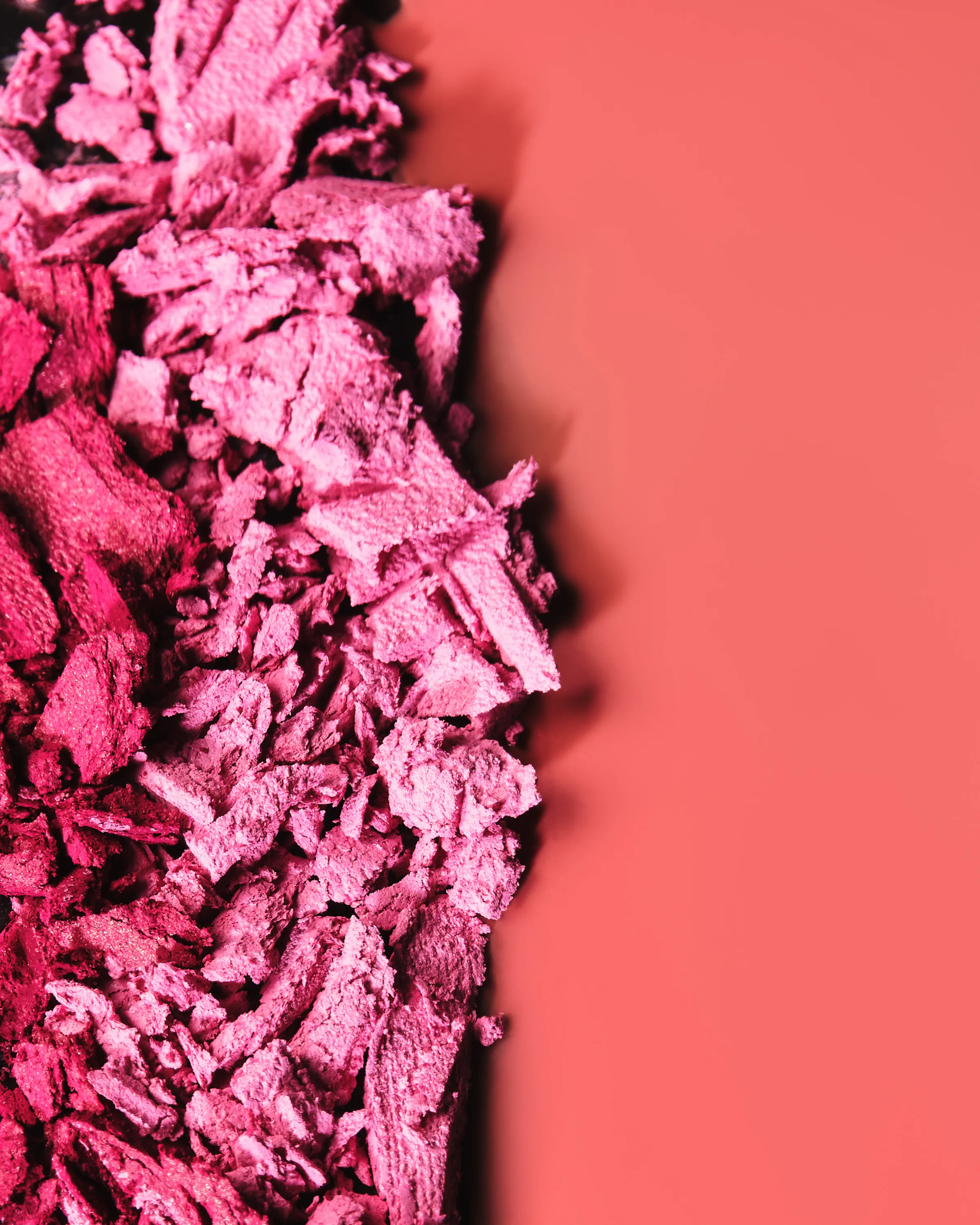 Crushed pink pressed powder swatch against a coral background, for Kylie Cosmetics.