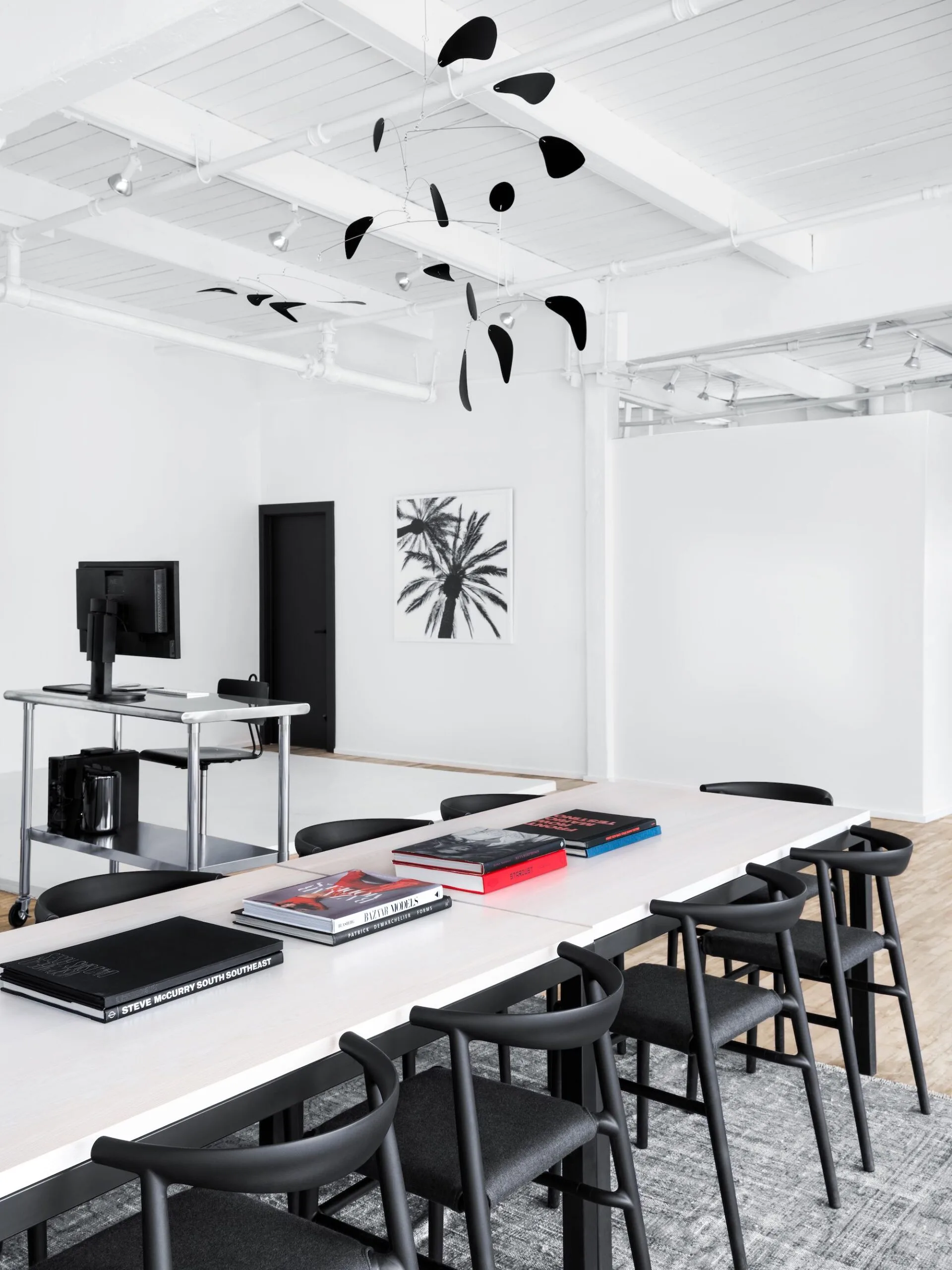 Studio 1 at Slate Studios with a long white table, black chairs, art books, a black mobile and a digital tech cart.