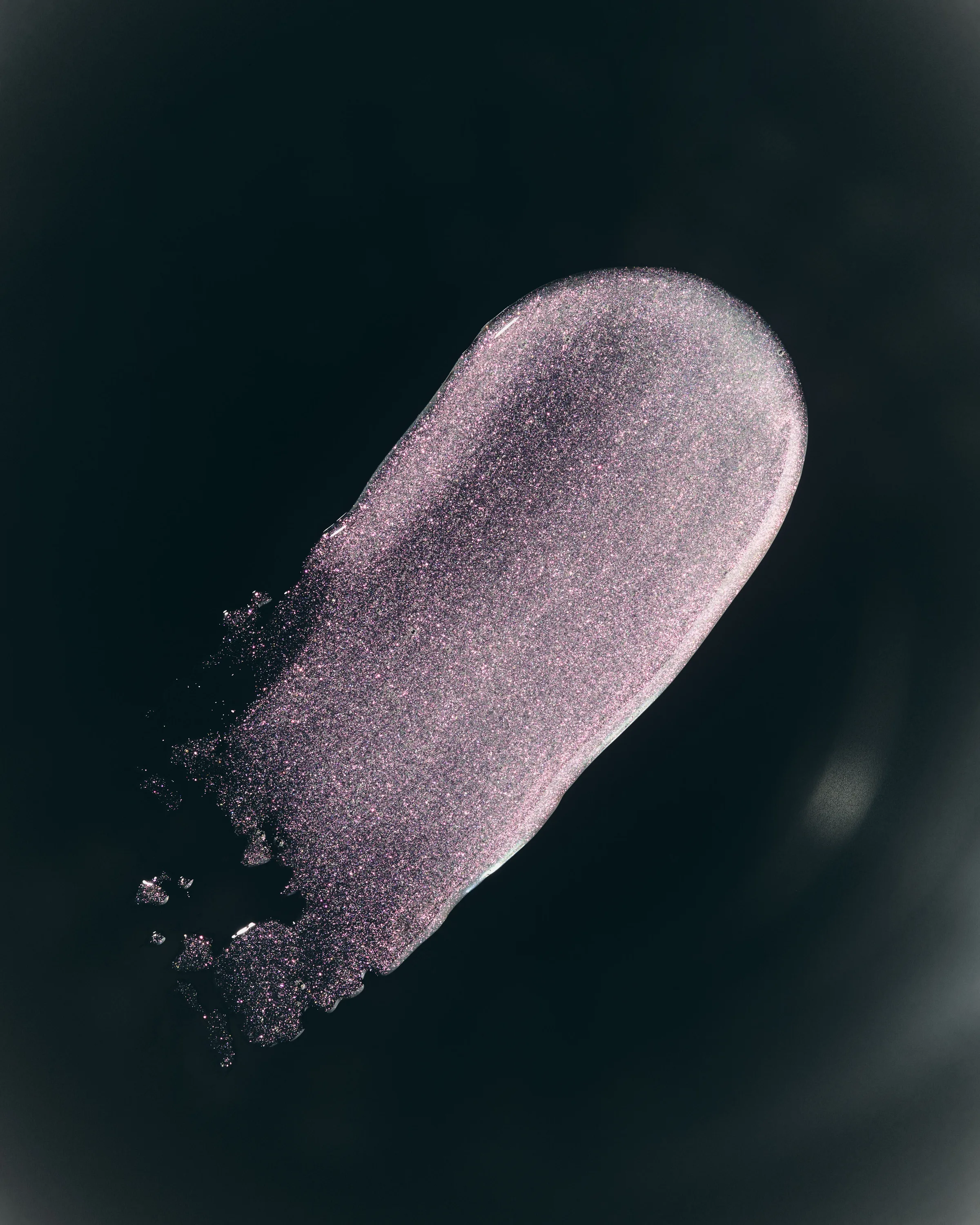 Swatch of shimmering pink-violet lip glaze smeared across a black background, for Kylie Cosmetics.