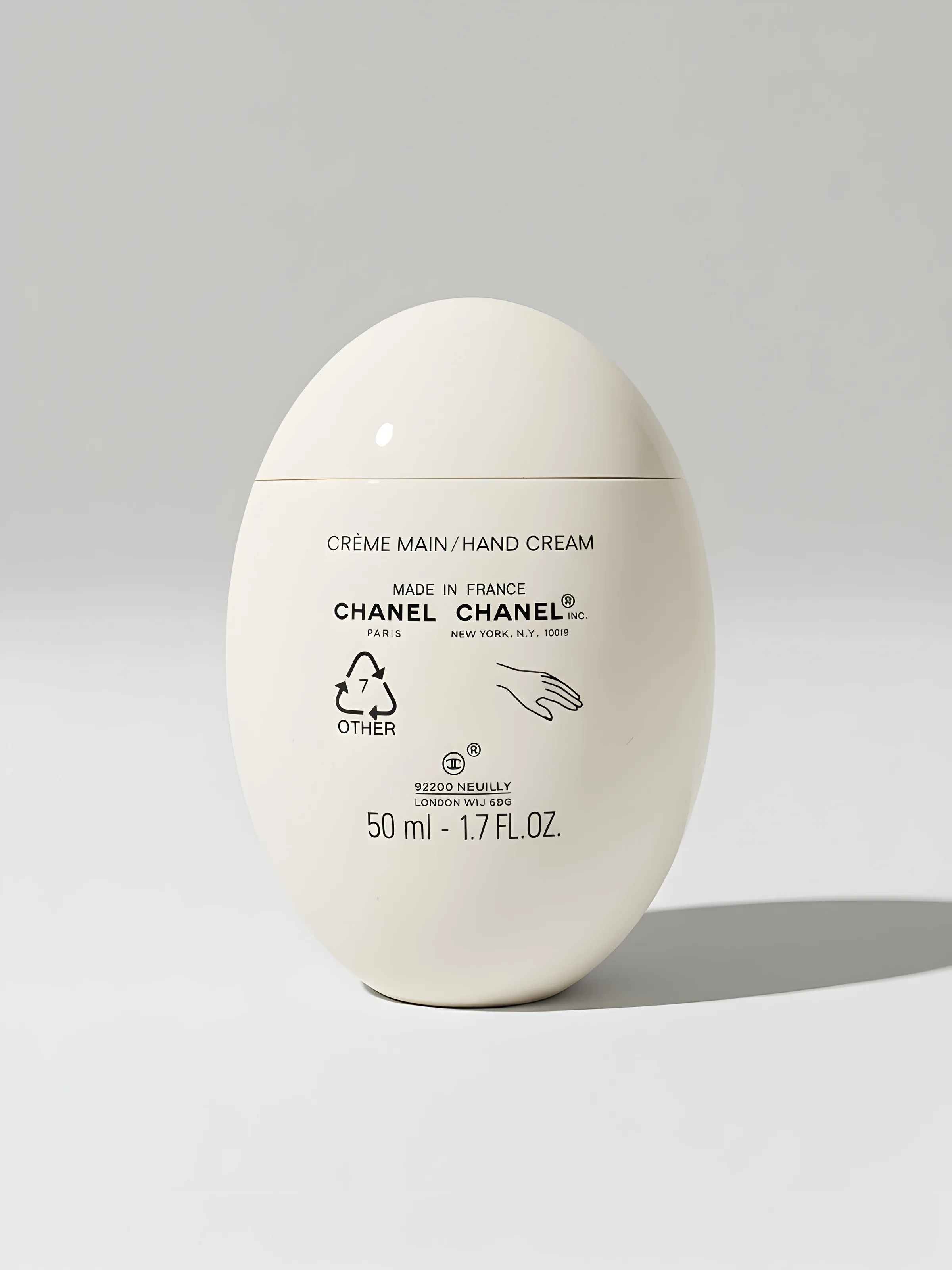 AI image of a white egg-shaped hand cream bottle standing on a pale grey background with a soft shadow. Chanel AI Concept.