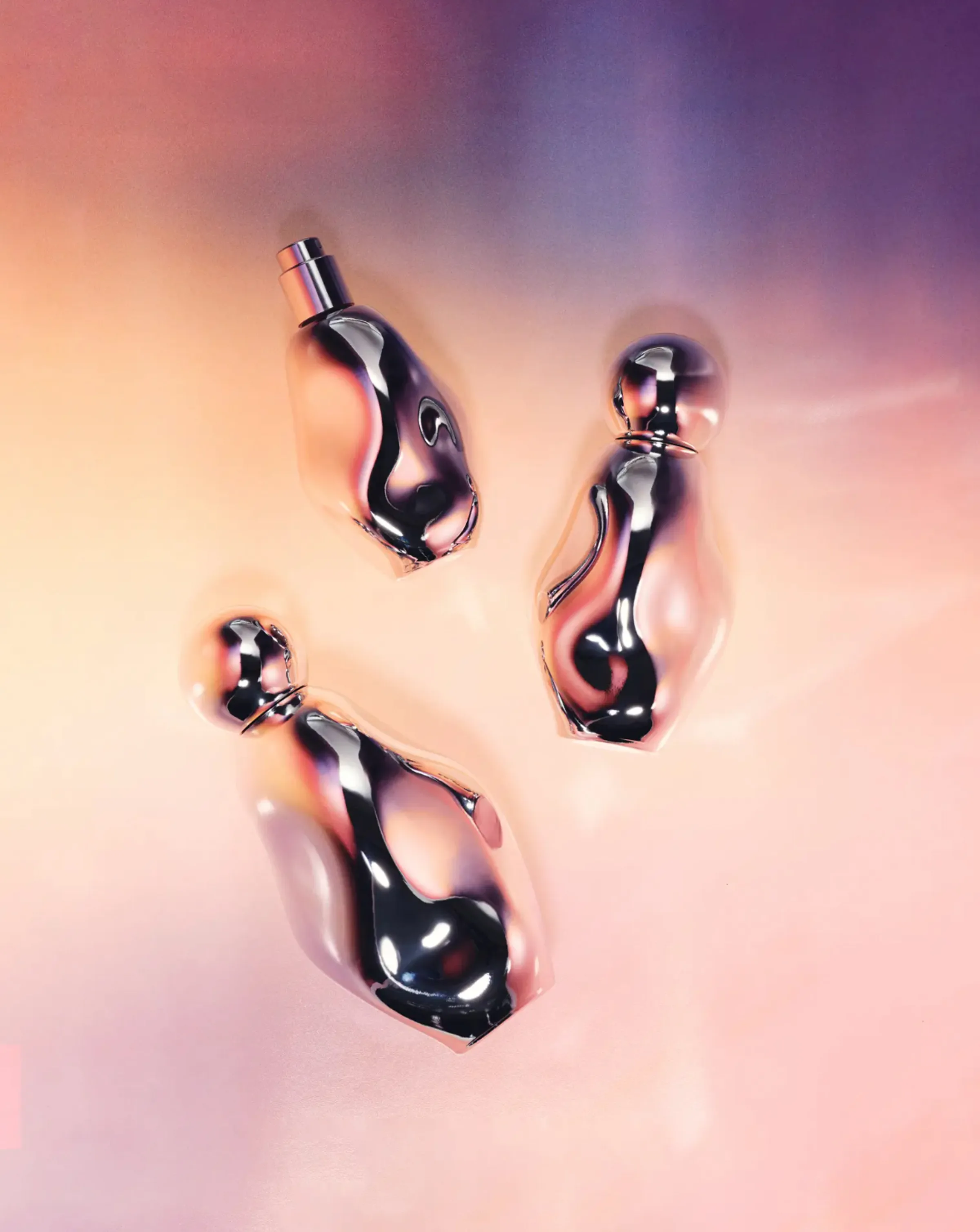 Three sculpted chrome perfume bottles lying on a glossy peach and violet gradient surface, for Kylie Cosmetics.