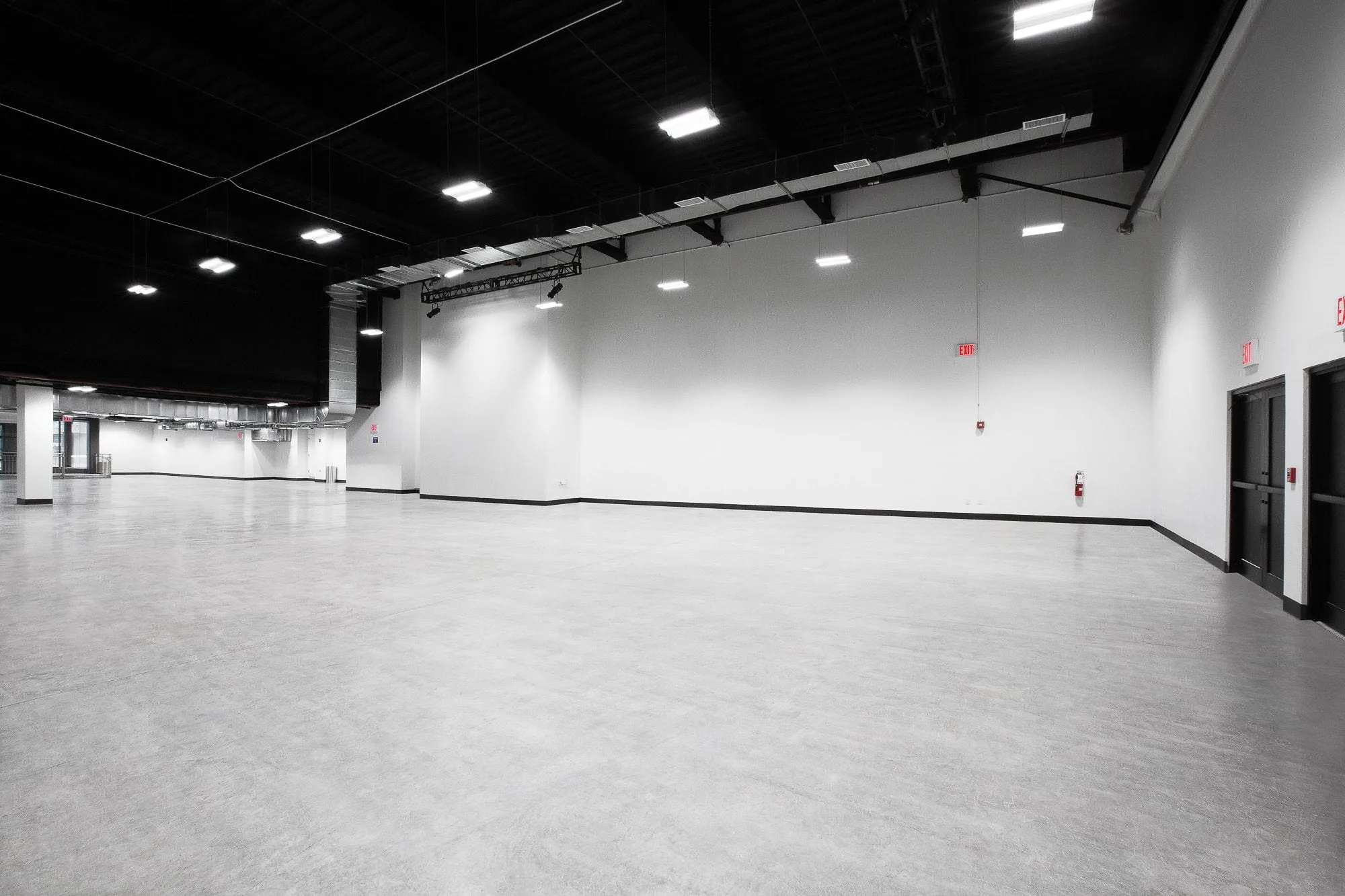 Empty Studio 2 stage at Slate Studios with white walls, grey concrete floor, black ceiling and overhead lights.