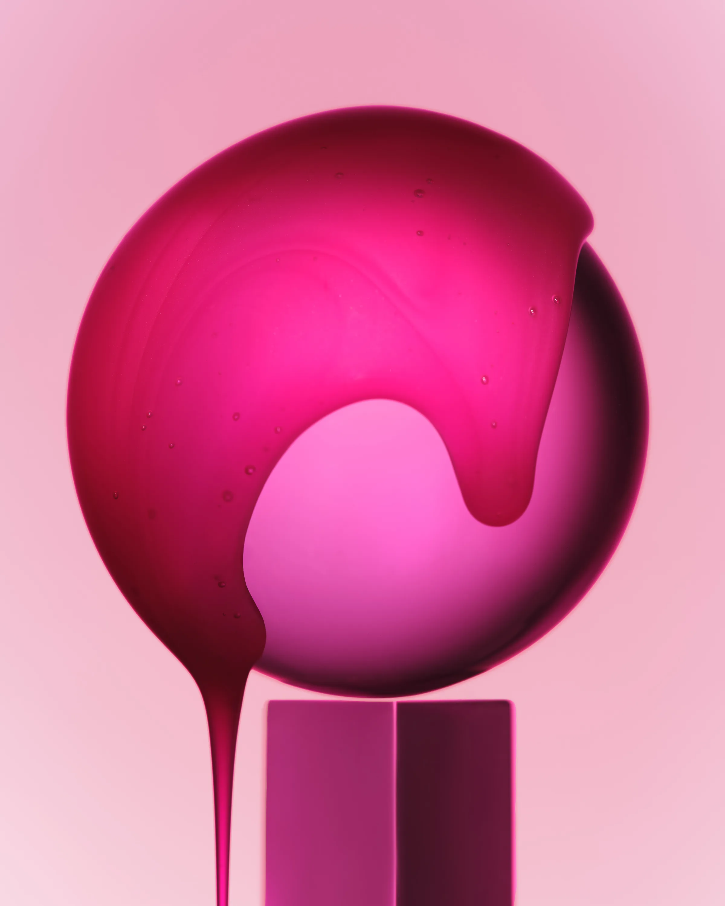 Candy pink lip glaze dripping over a glossy sphere on a pink pedestal against a pink backdrop, for Kylie Cosmetics.