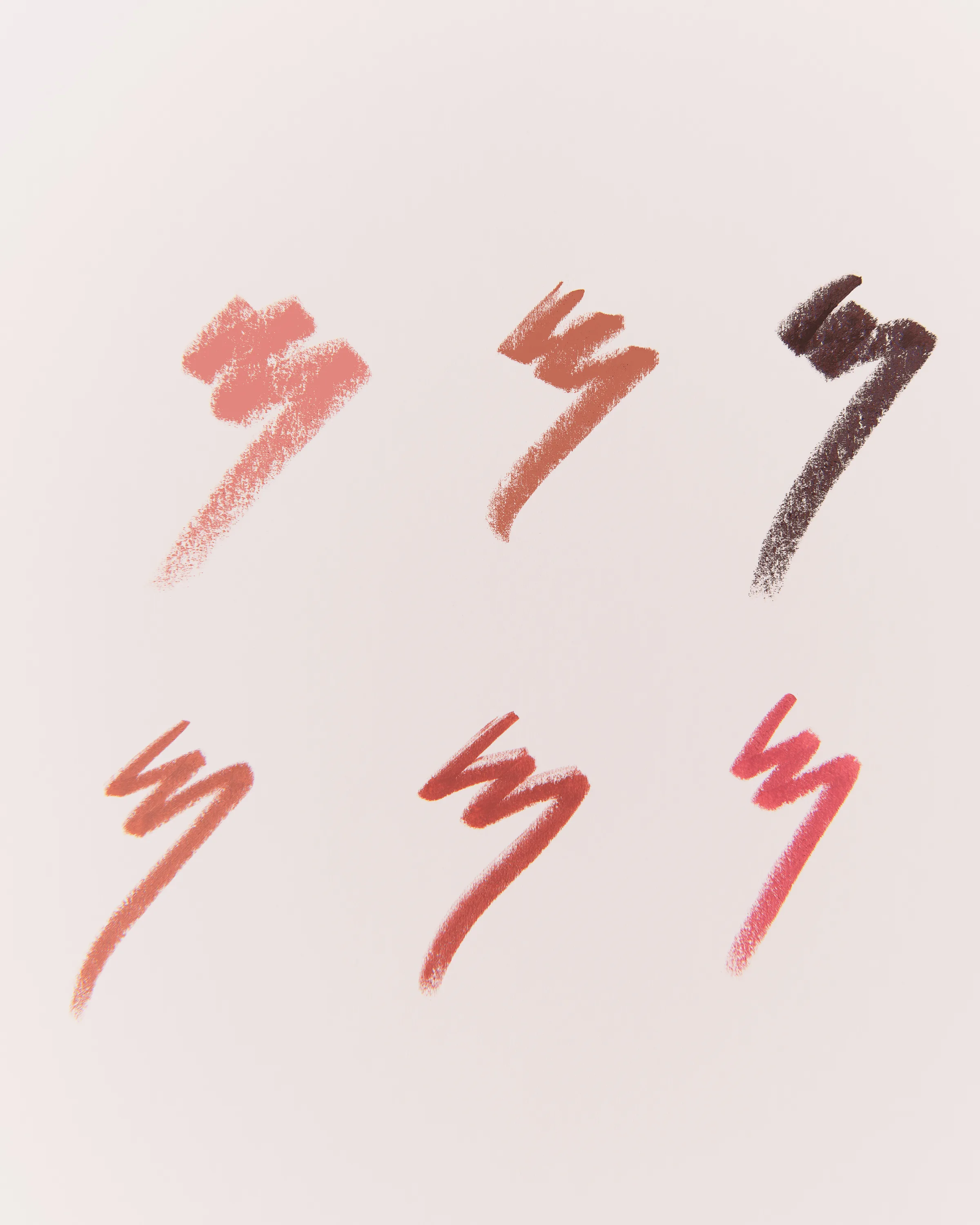 Six lip liner swatches in nude, pink, terracotta, red and deep plum scribbled on a pale pink background, for Kylie Cosmetics.