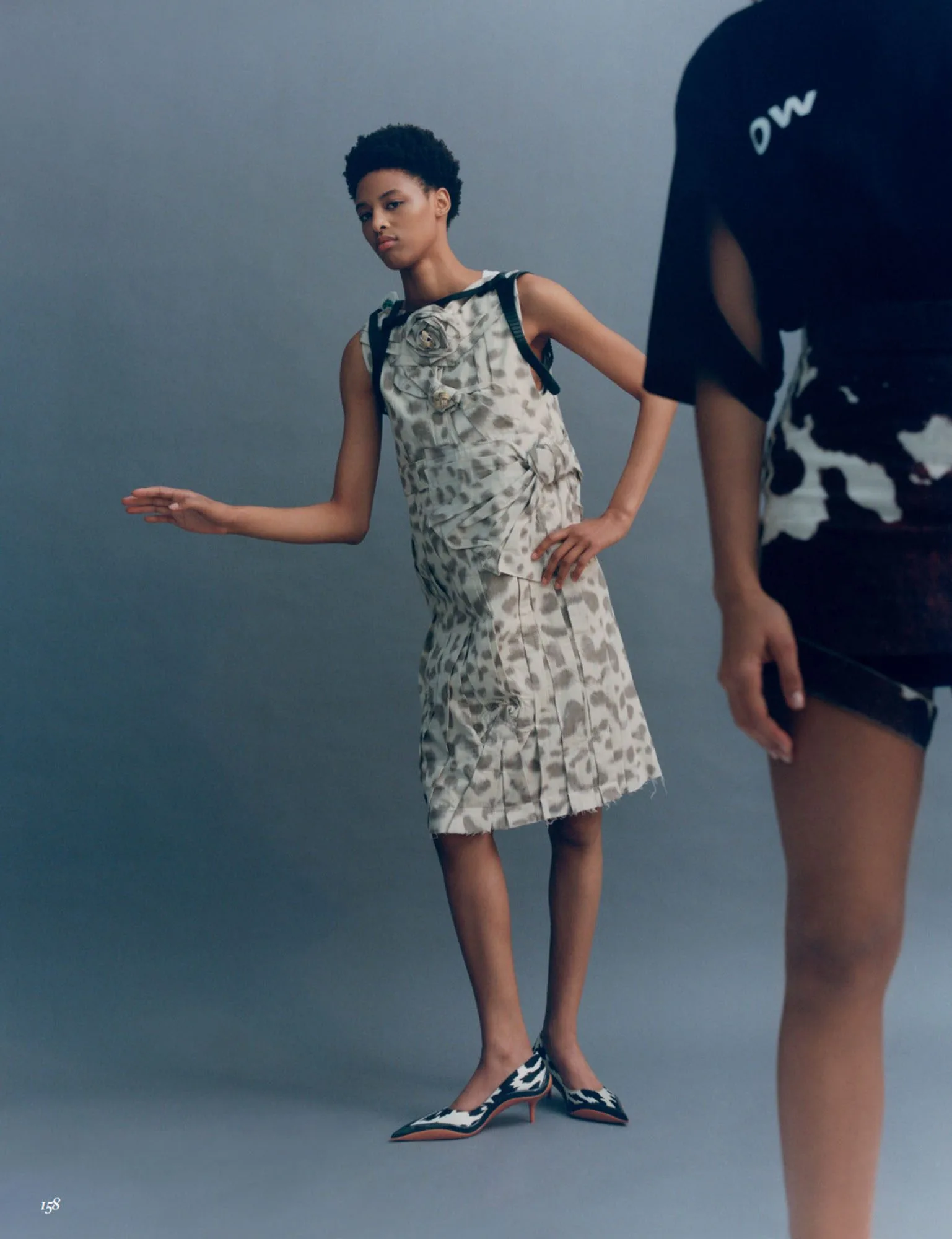 Model in a sleeveless leopard print dress with rosette and cow print kitten heels on a grey backdrop, for Vogue Mexico.