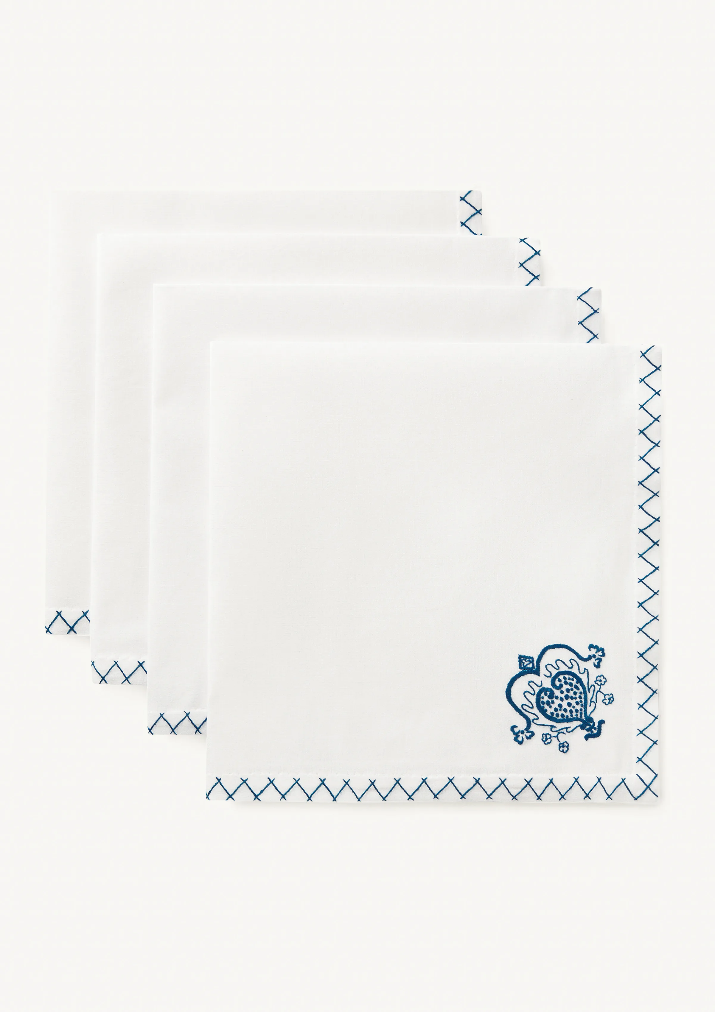 Four white cotton napkins fanned out with blue cross-stitch borders and an embroidered heart motif, for Rhode.