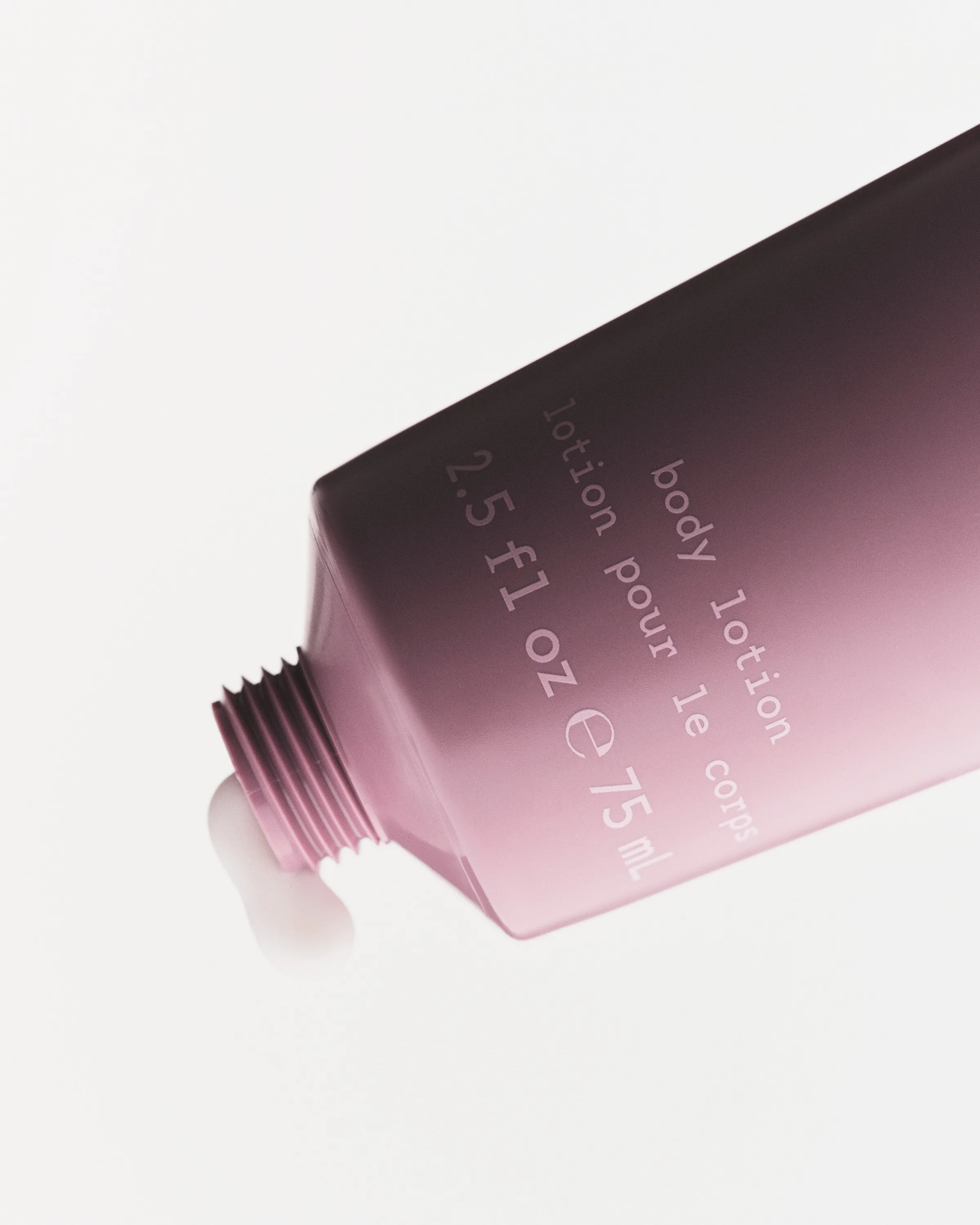 Pink-to-plum gradient body lotion tube, uncapped with lotion squeezing from the nozzle, on white, for Kylie Cosmetics.