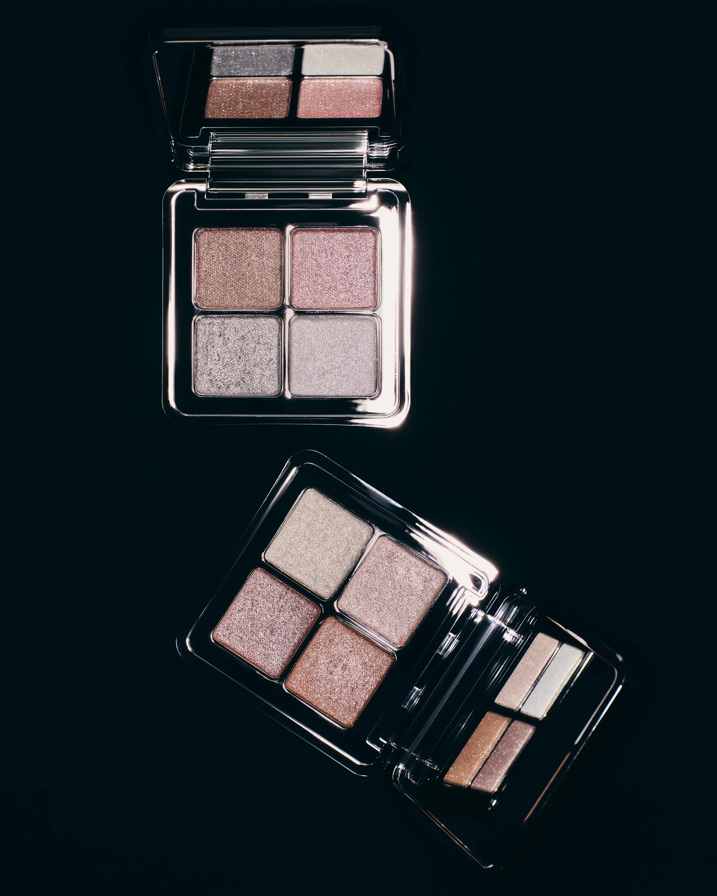 Two open mirrored eyeshadow quads in shimmering pink, bronze and silver shades on a black background, for Kylie Cosmetics.