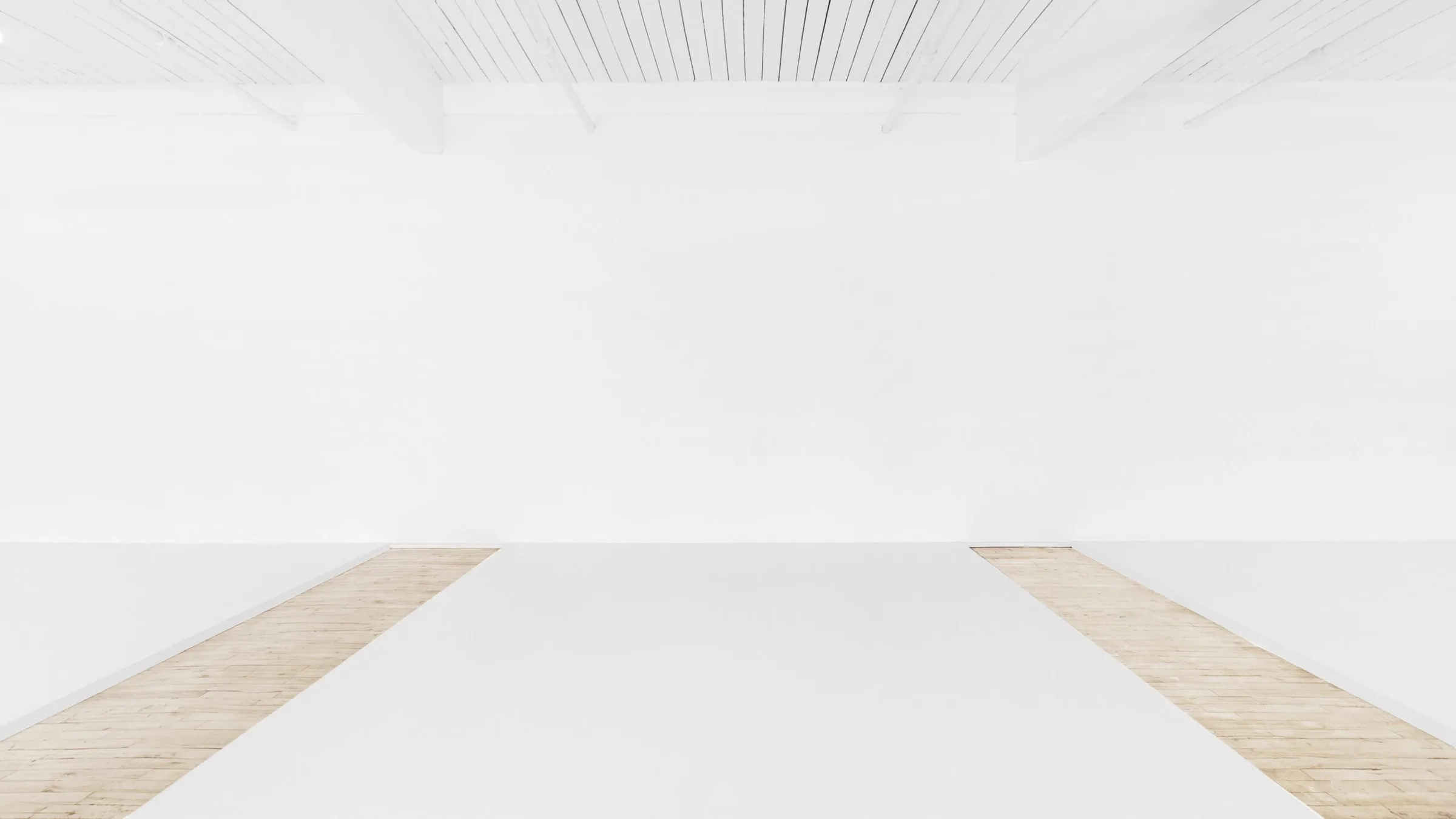 Bright white stage with a white cyclorama wall, white floor paper over wood planks and a white beamed ceiling.