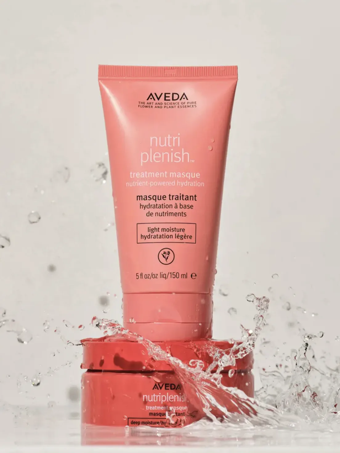 Coral Nutriplenish treatment masque tube stacked on a jar with water splashing around it on a pale grey background, for Aveda.