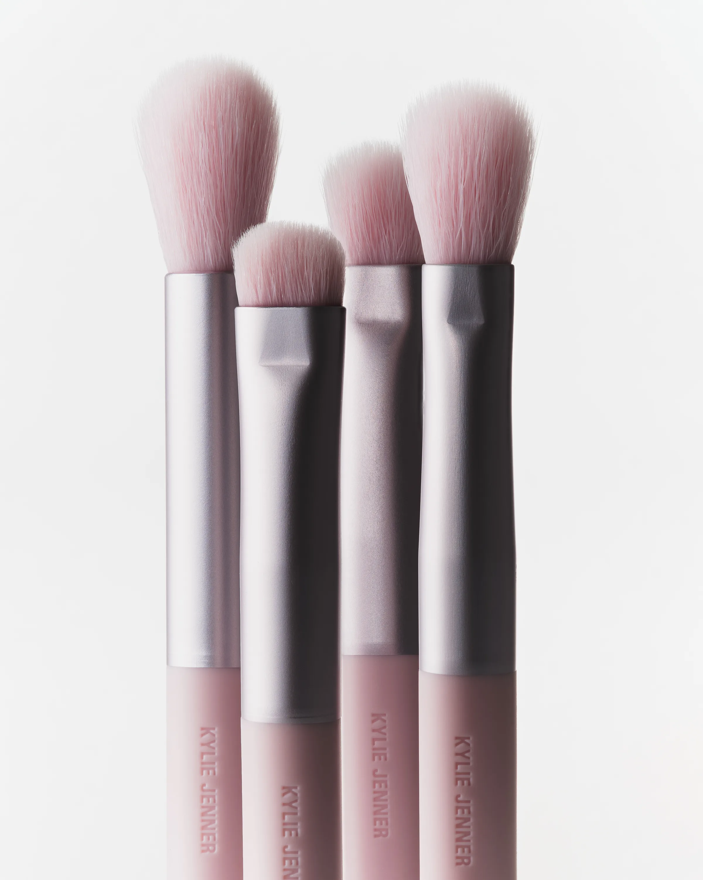 Four pink eye makeup brushes with silver ferrules standing upright against a white background, for Kylie Cosmetics.