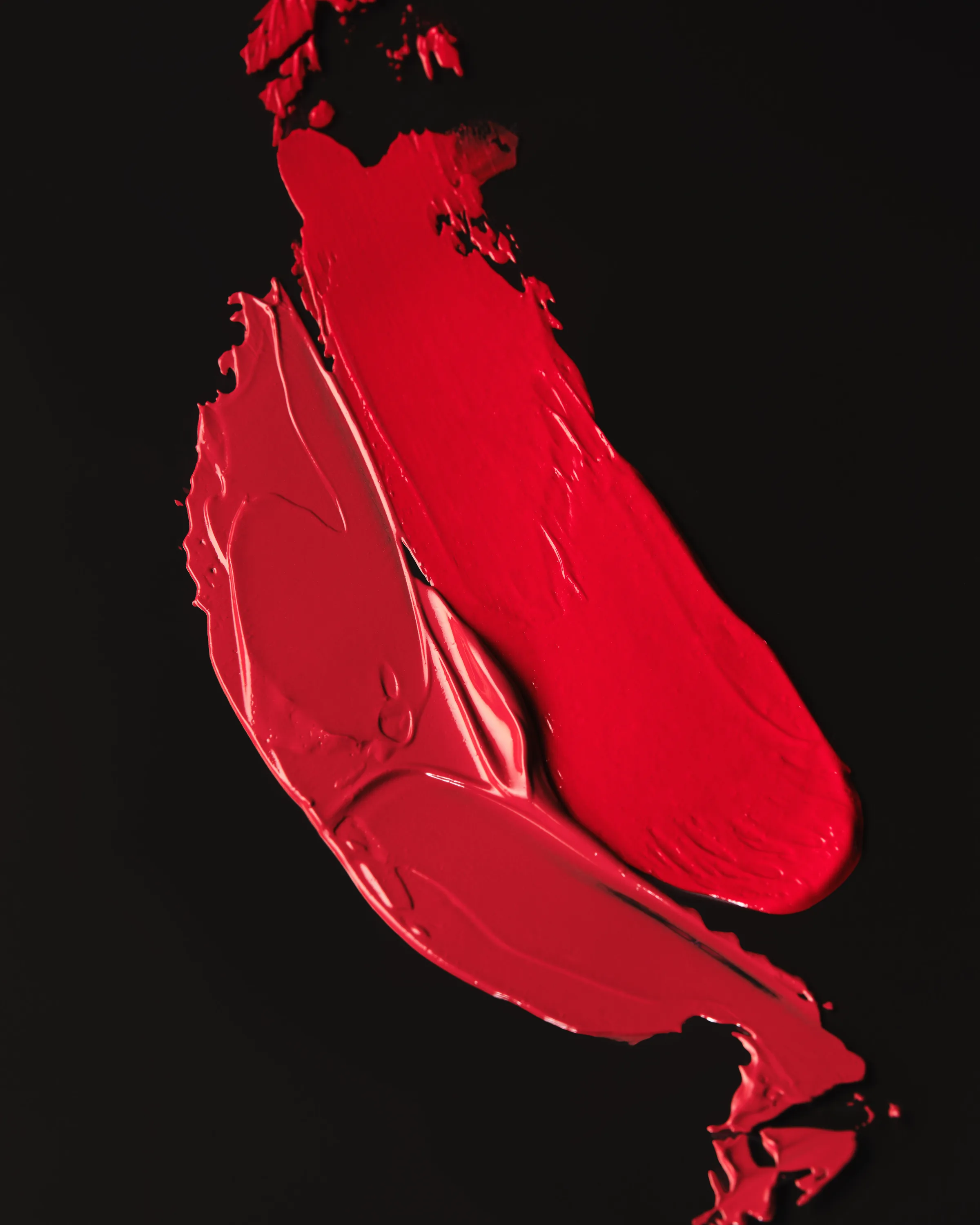 Two smeared red lipstick swatches, one matte and one glossy, on a black background, for Kylie Cosmetics.