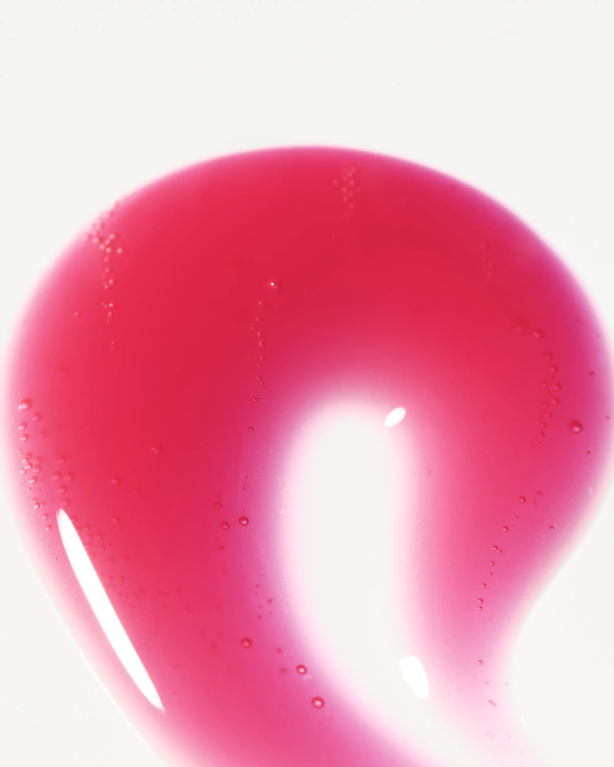 Glossy cranberry-red lip gloss swatch with tiny air bubbles on a white background, for Kylie Cosmetics.