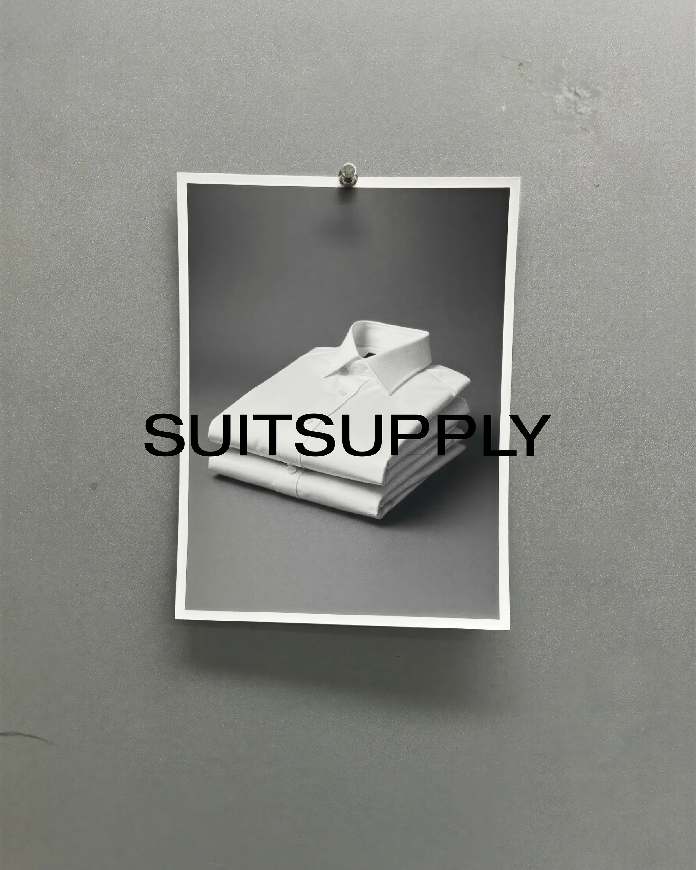 AI image of a pinned print showing folded white dress shirts on a grey wall, overlaid with the Suitsupply wordmark. Suitsupply AI Concept.