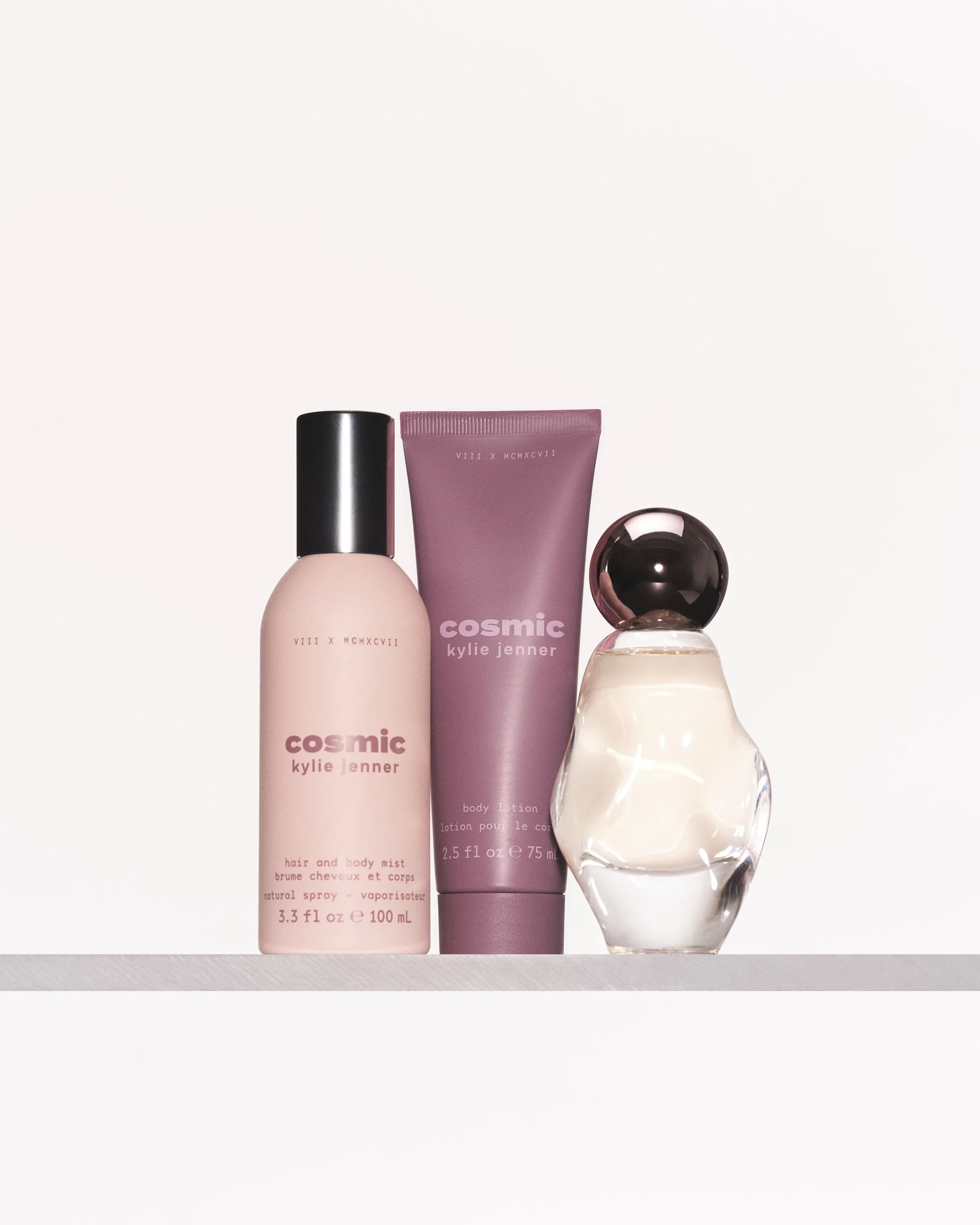 Cosmic hair and body mist, body lotion tube and sculpted perfume bottle on a white shelf, for Kylie Cosmetics.