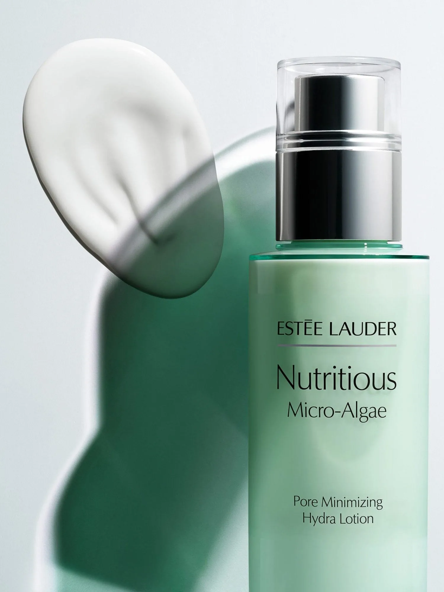 Green Nutritious Micro-Algae lotion bottle with silver pump beside a white cream swatch and green shadow, for Estée Lauder.