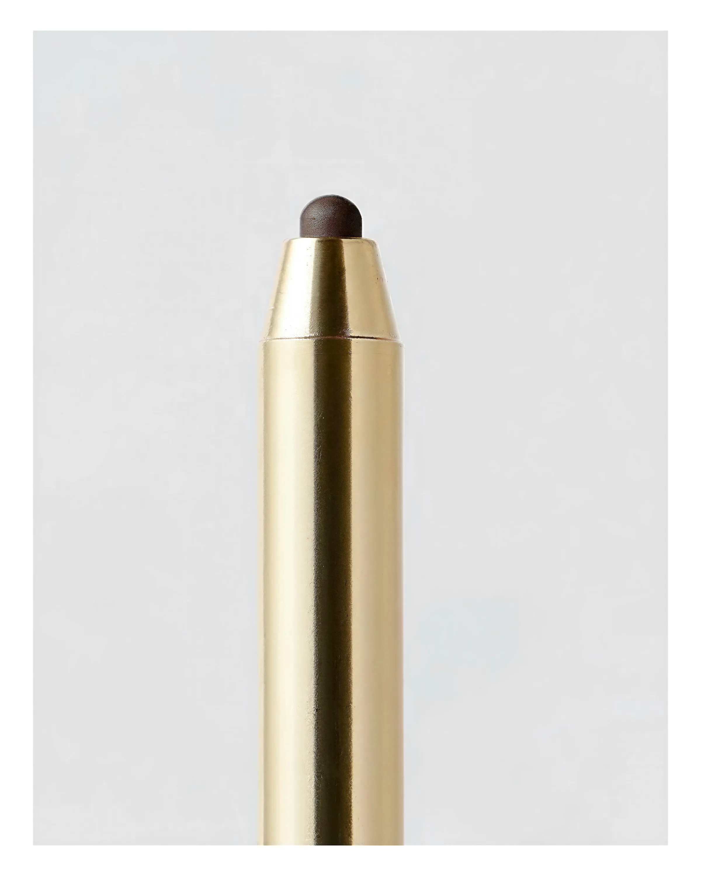 AI image of a gold eyeliner pencil with a dark brown tip against a pale grey background. Merit AI Concept.