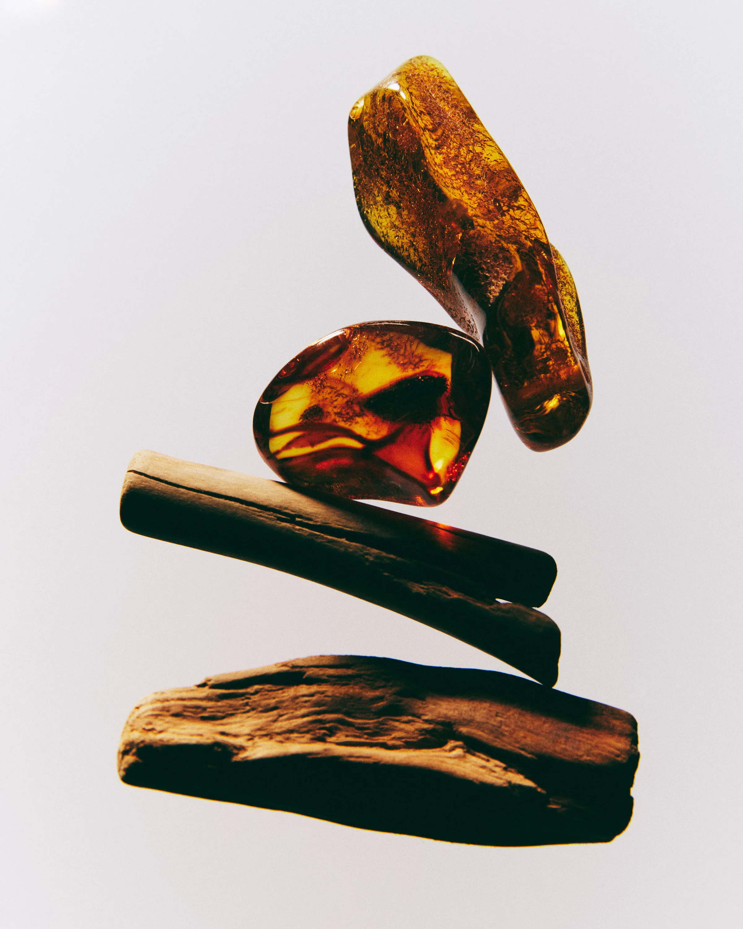 Still life of polished amber stones balanced on driftwood pieces against a grey background, for Kylie Cosmetics.
