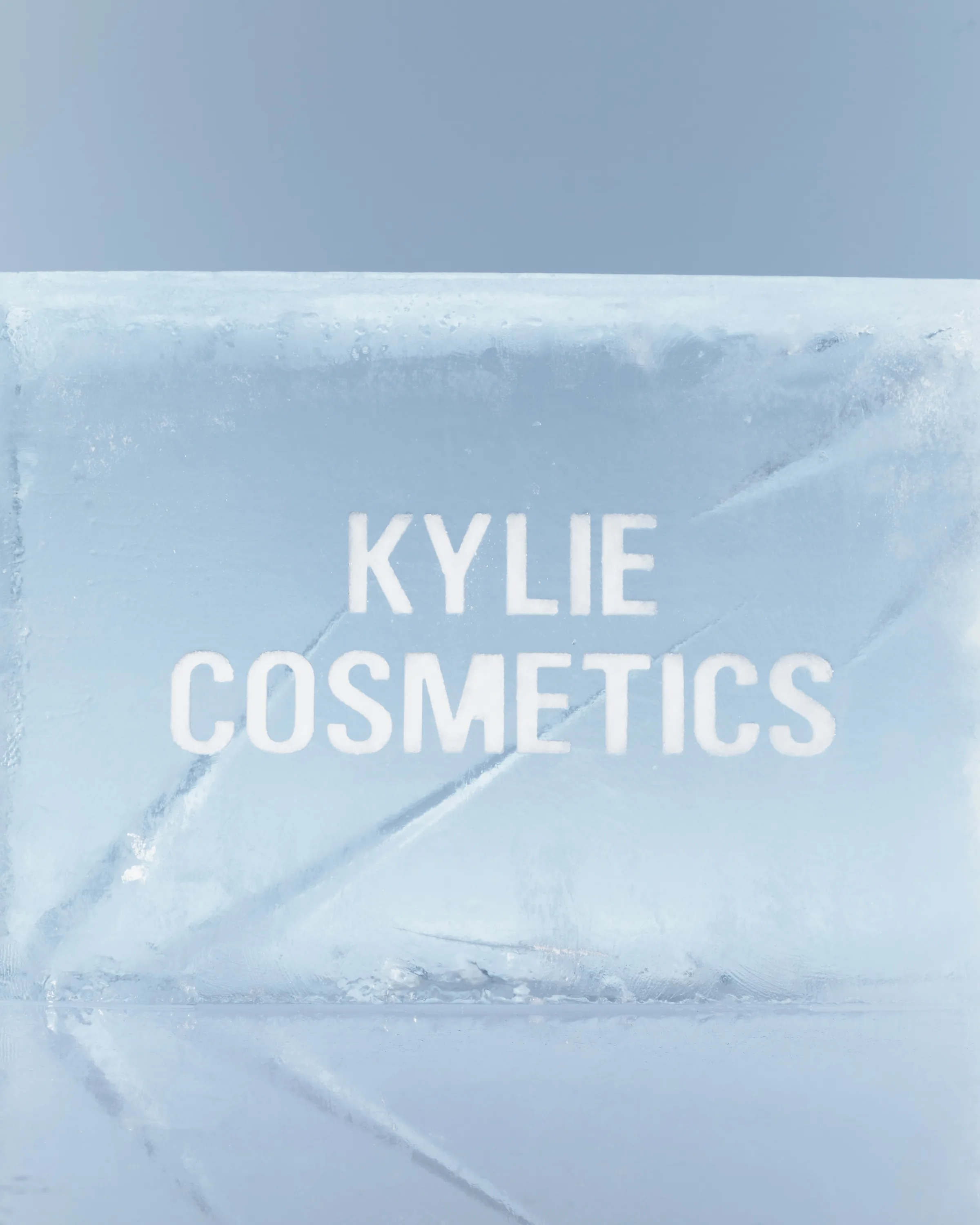 Kylie Cosmetics name etched in white on a clear ice block against a pale blue background, for Kylie Cosmetics.