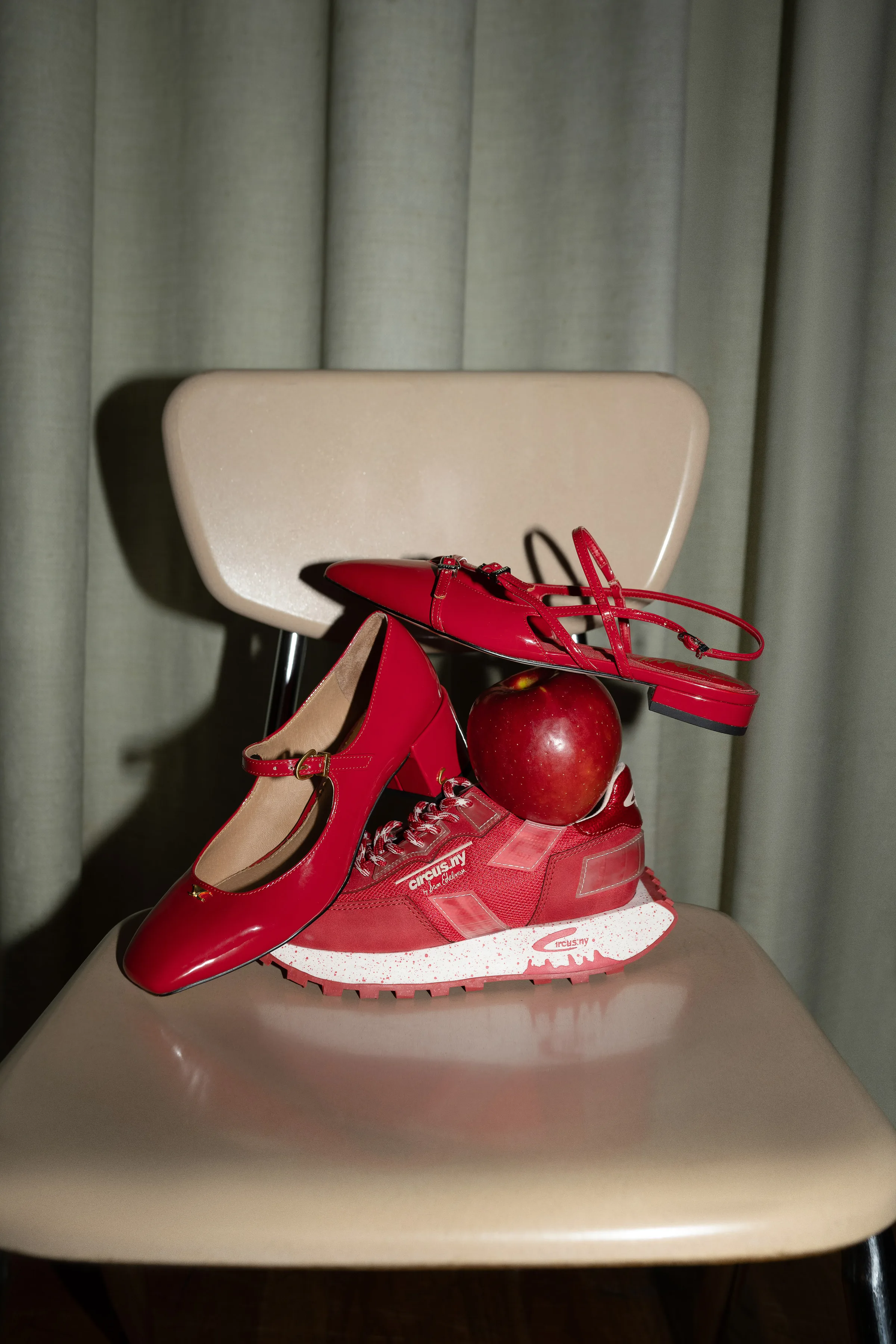 Red patent Mary Janes, slingback flats and a sneaker stacked with an apple on a beige school chair, for Sam Edelman.