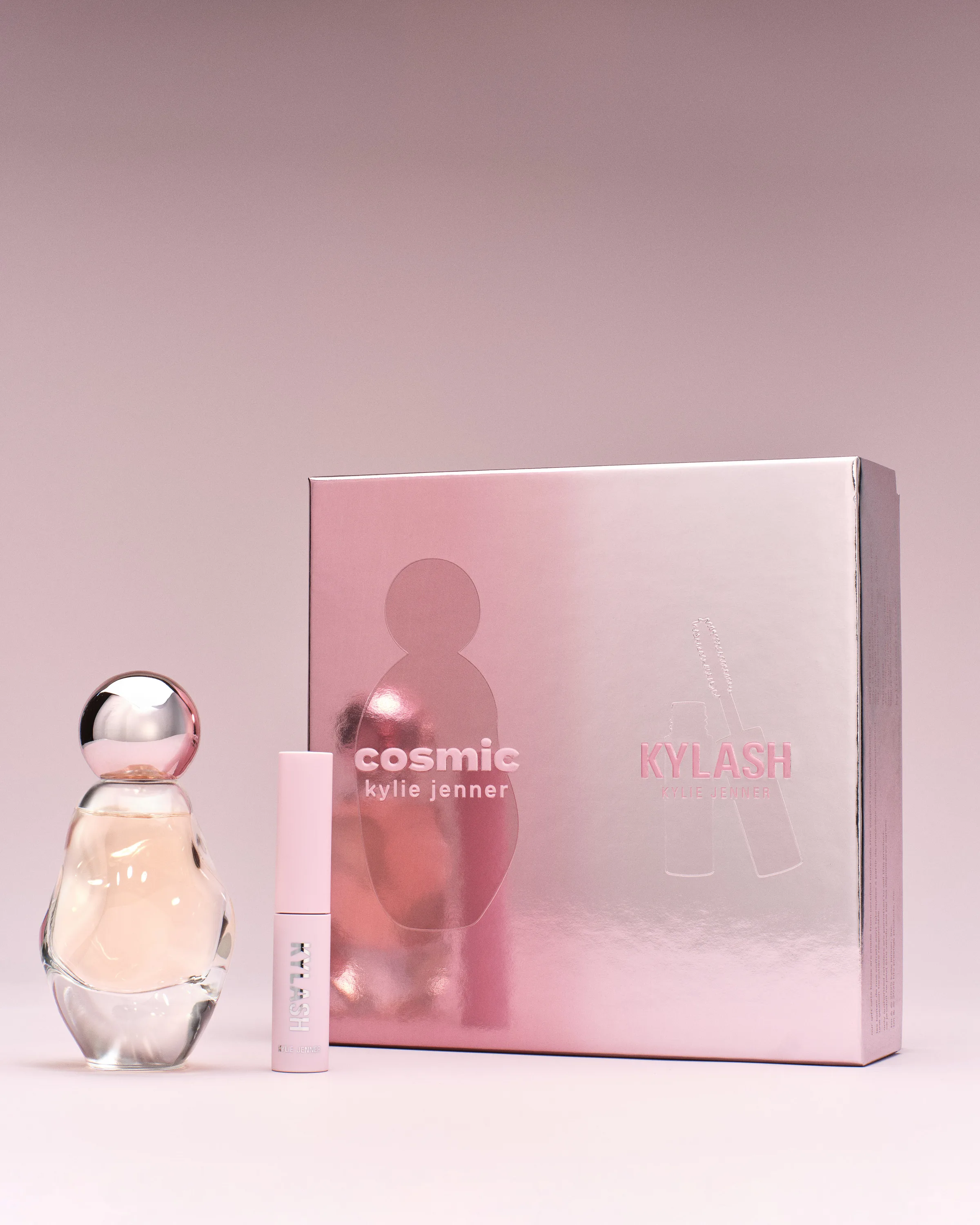 Cosmic perfume bottle and Kylash mascara beside a metallic pink gift box on a soft pink background, for Kylie Cosmetics.