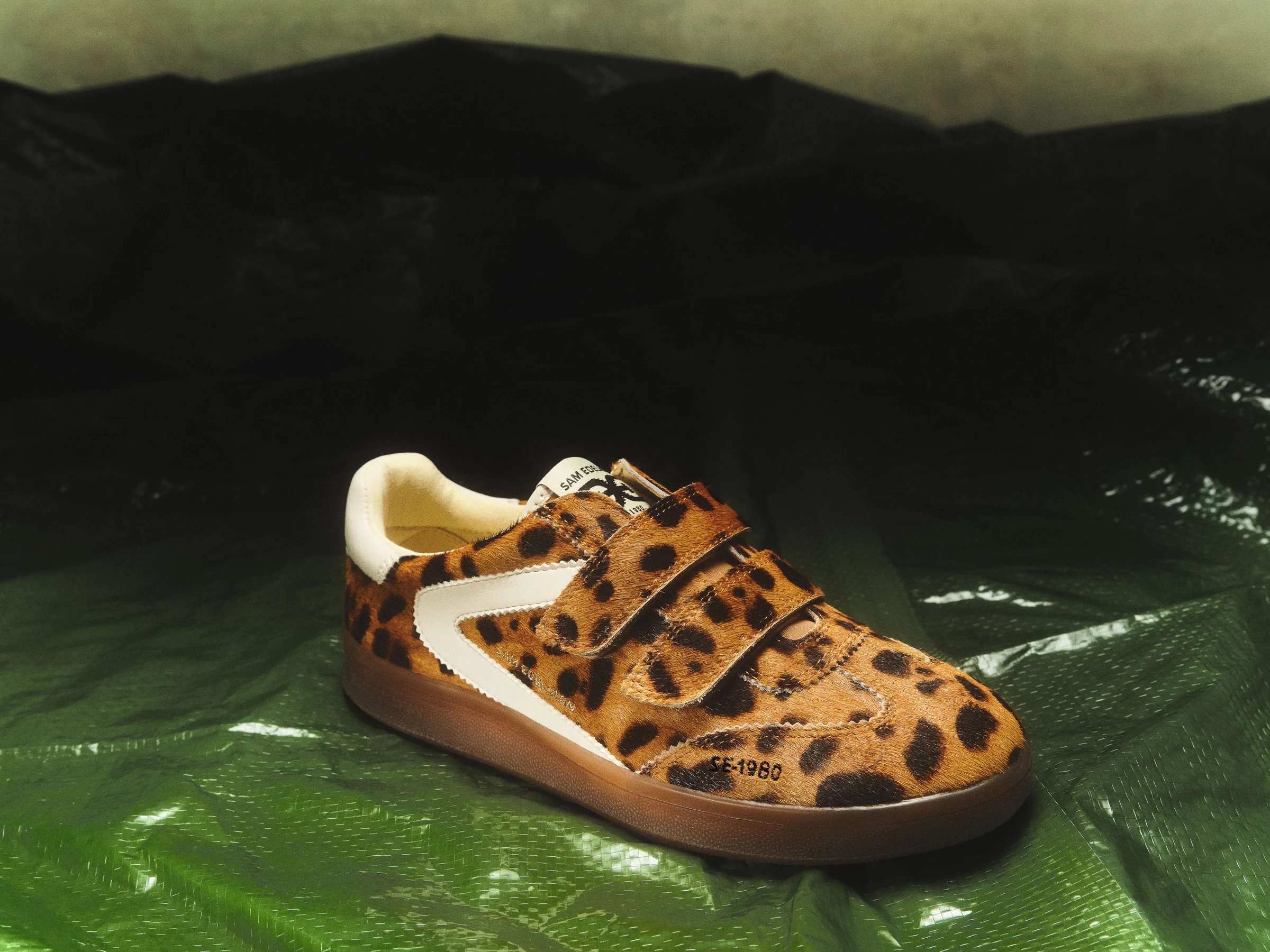 Leopard-print calf hair sneaker with white stripe and velcro straps on green and black plastic sheeting, for Sam Edelman.